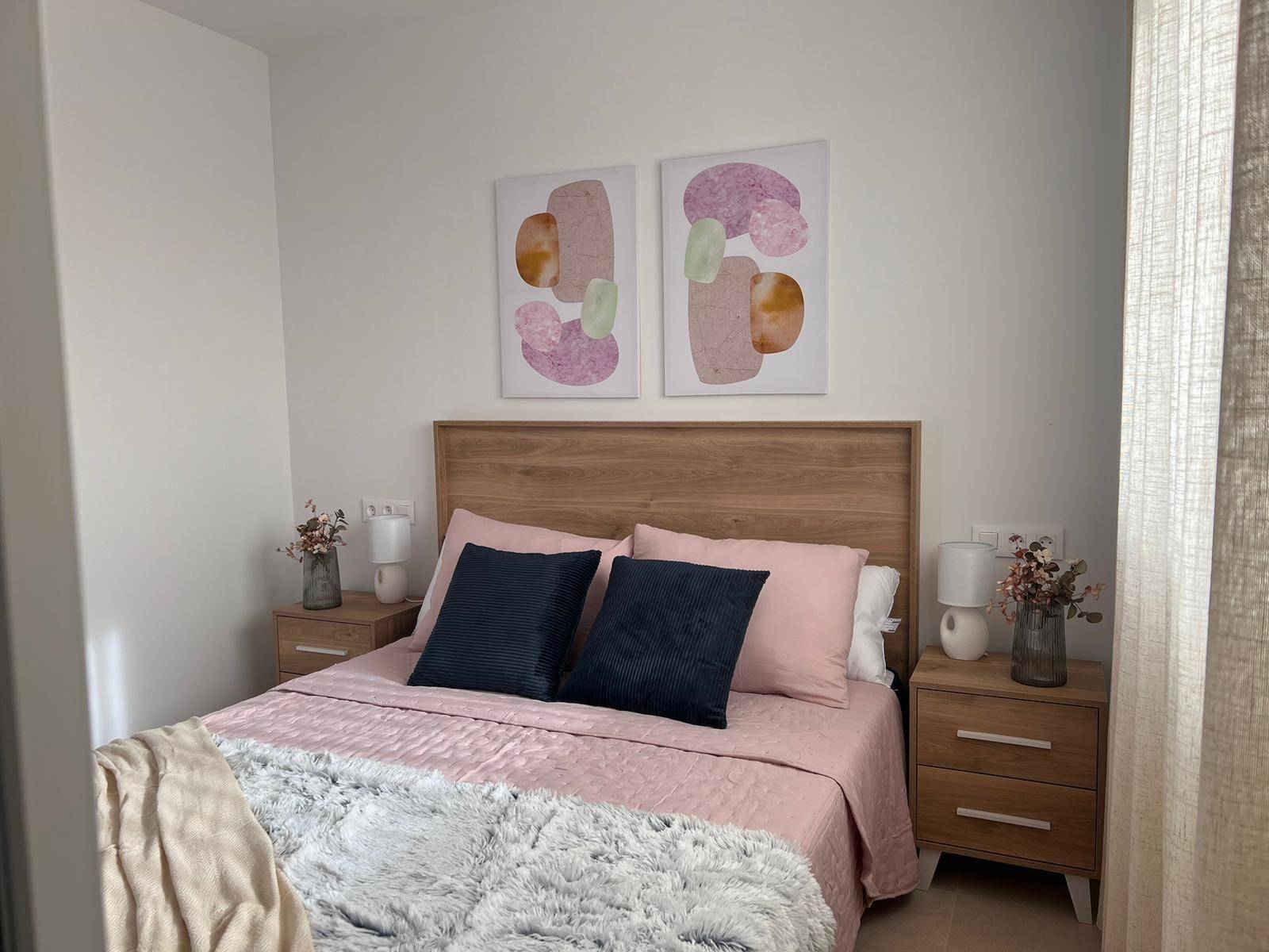 Gemütliches Schlafzimmer mit Doppelbett, Holzkopfteil und Nachttischen in hellem Ambiente.