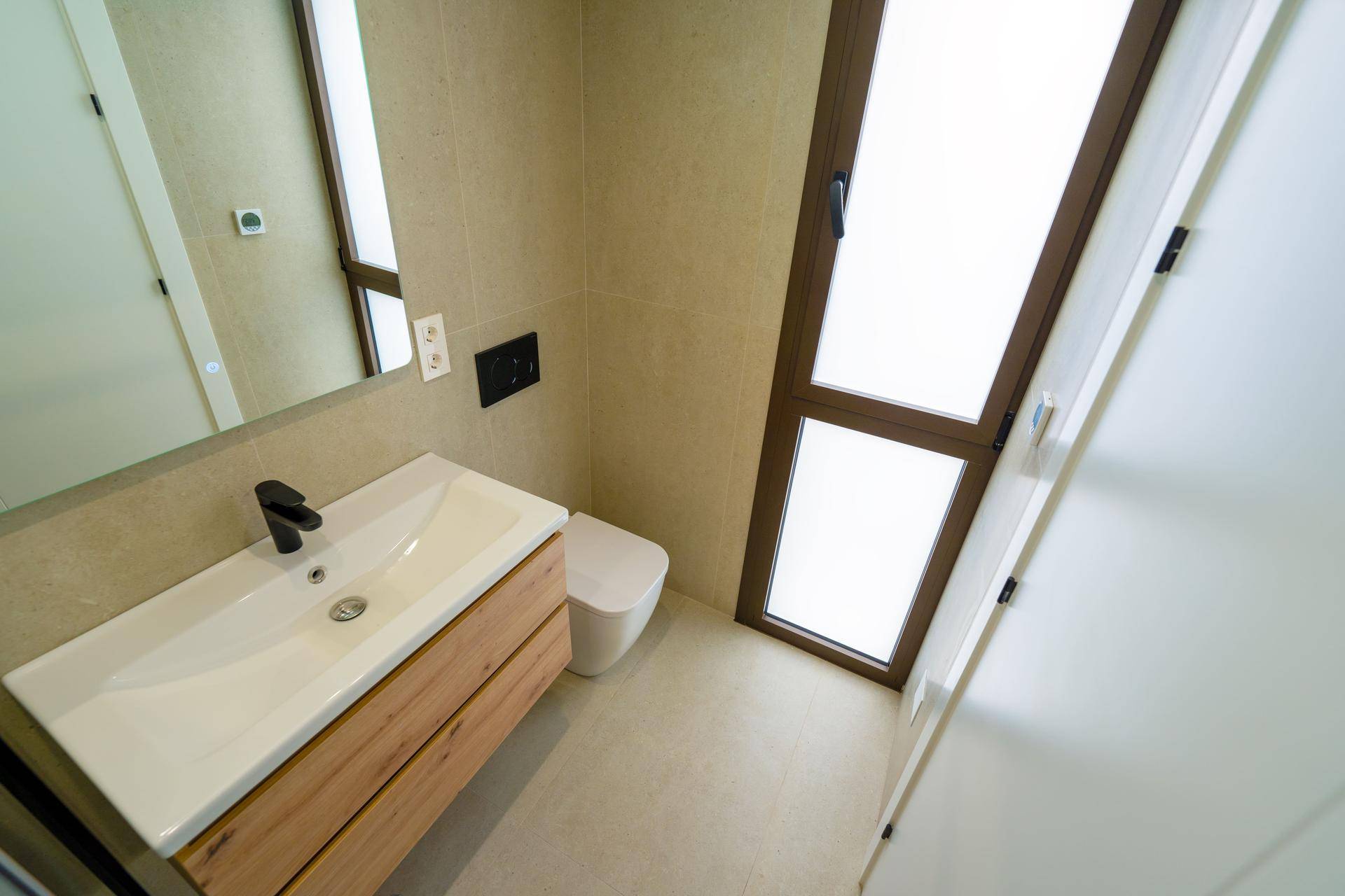 Kompaktes Badezimmer mit Einzelwaschbecken, Toilette und einem Fenster für Belüftung.