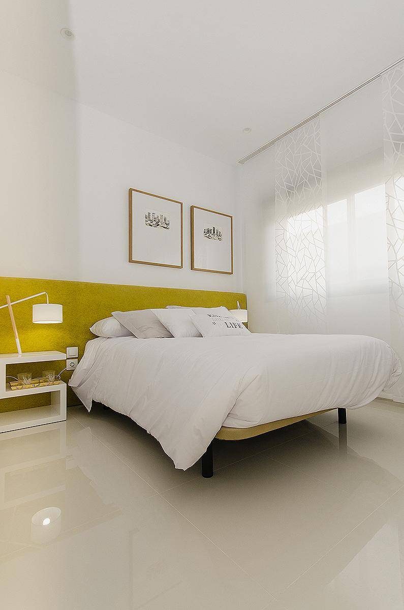 Lichtdurchflutetes Schlafzimmer mit modernem Design, gelbem Akzent und glänzenden Fliesen.