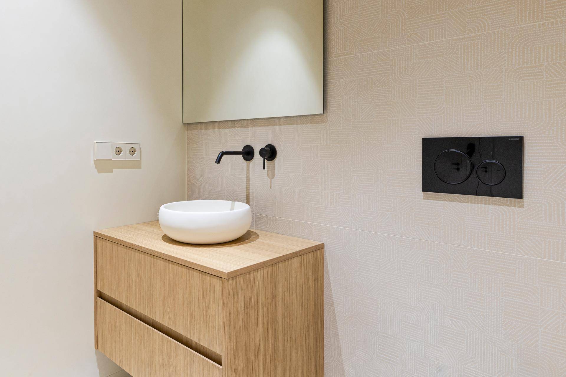 Detailaufnahme des modernen Waschtischs mit rundem Waschbecken und Spiegel im WC.