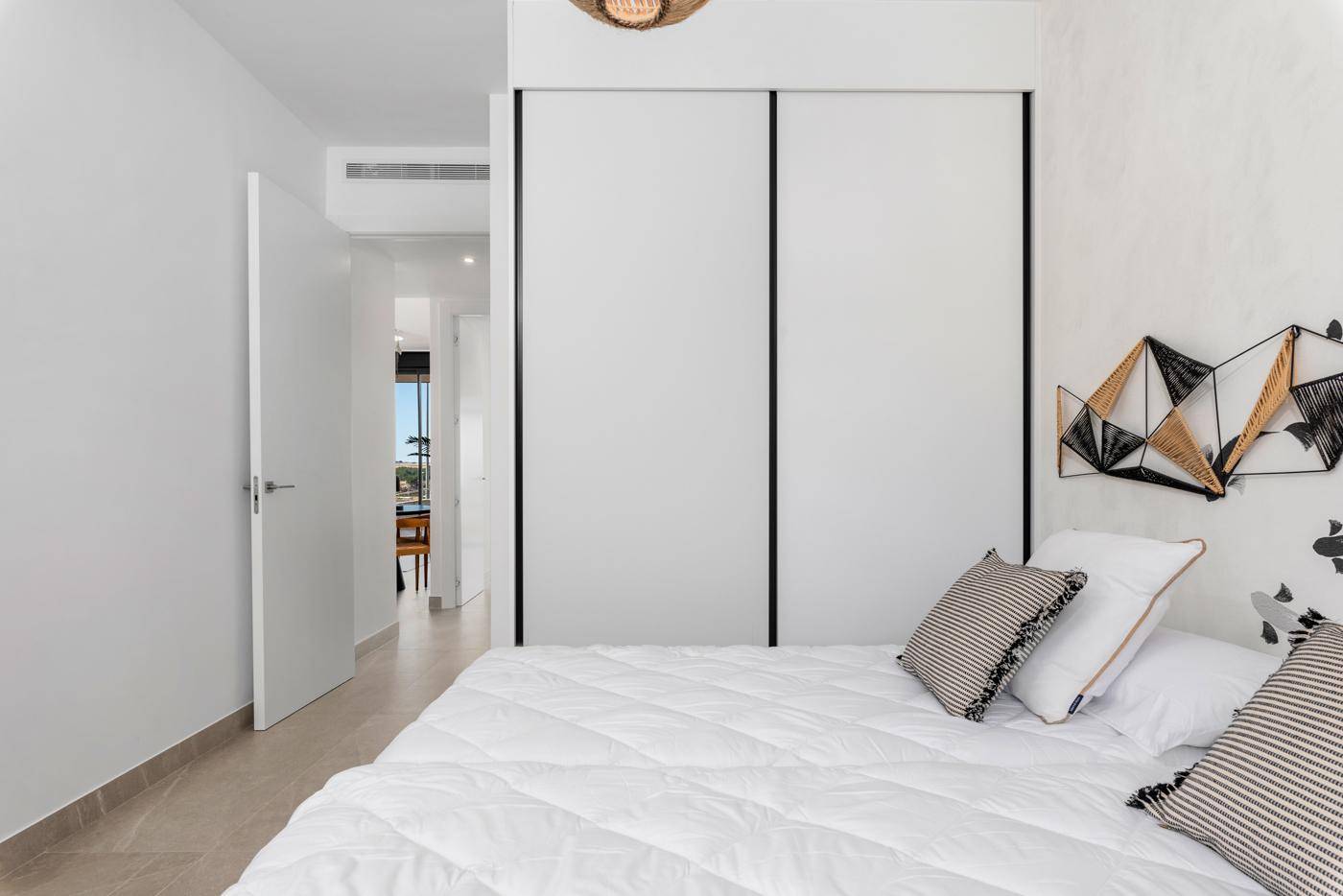 Schlafzimmer mit geschlossenen Einbauschränken, Doppelbett und kreativer Wandgestaltung.