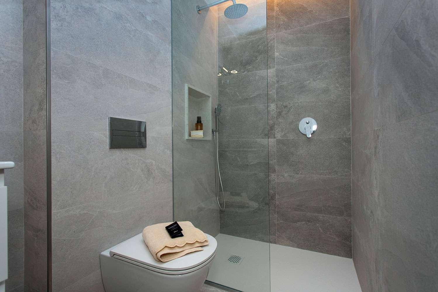Geräumige begehbare Dusche mit Regenduschkopf und modernen Fliesen, sehr komfortabel.