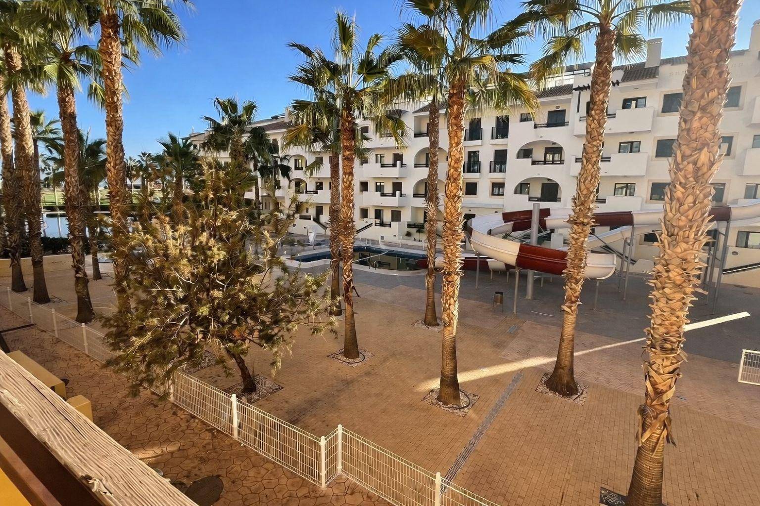 Außenbereich mit Palmen, Wasserrutsche und Blick auf die Apartmentgebäude.