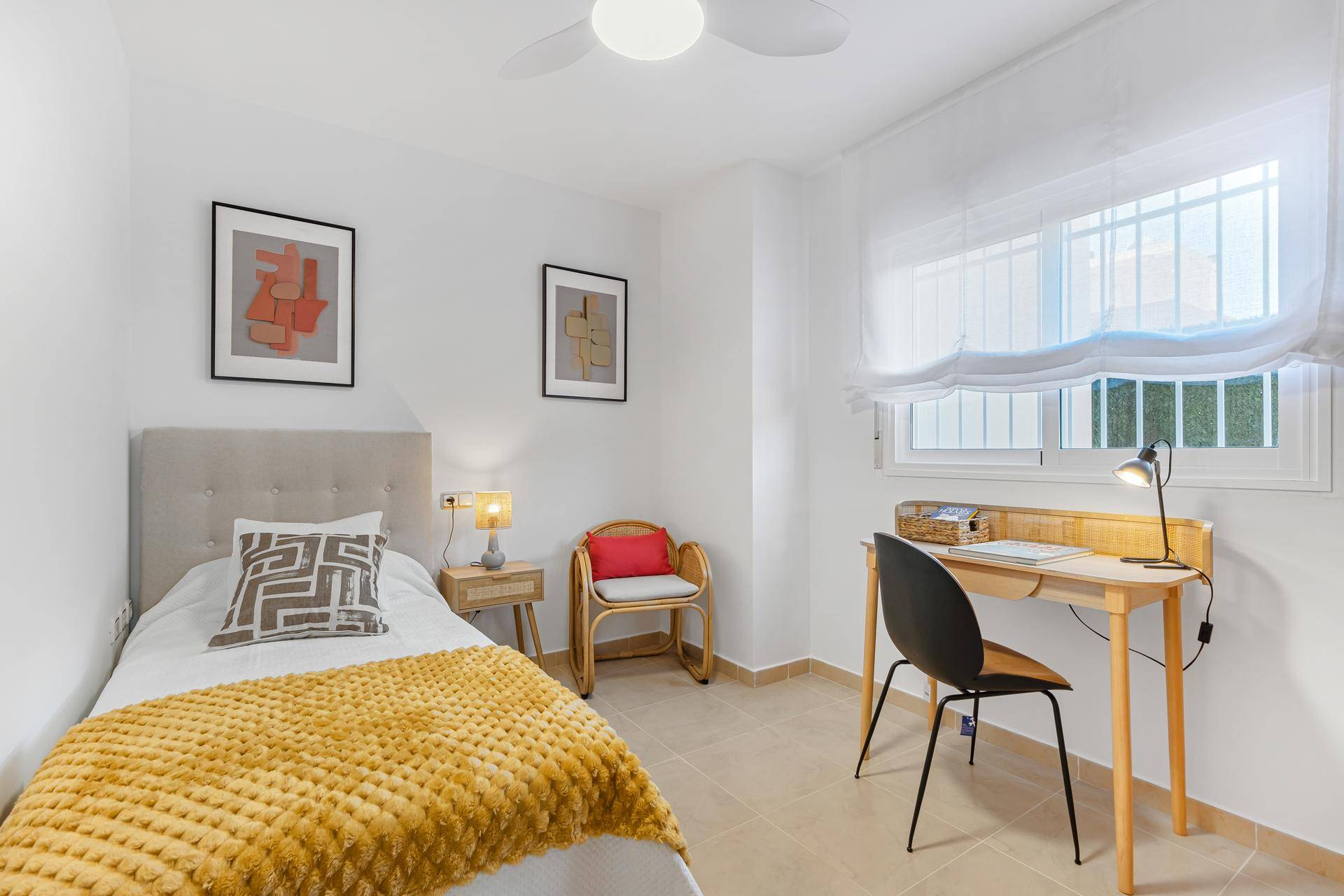 Gemütliches Einzelzimmer mit Schreibtisch, Stuhl und Fenster für natürliches Licht.