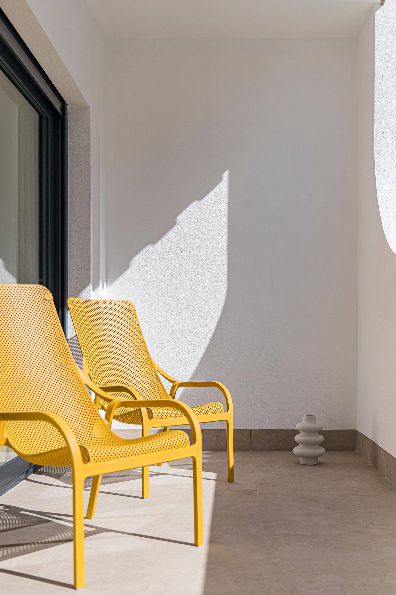 Sonniger Balkon mit modernen gelben Liegestühlen, ideal zum Entspannen im Freien.