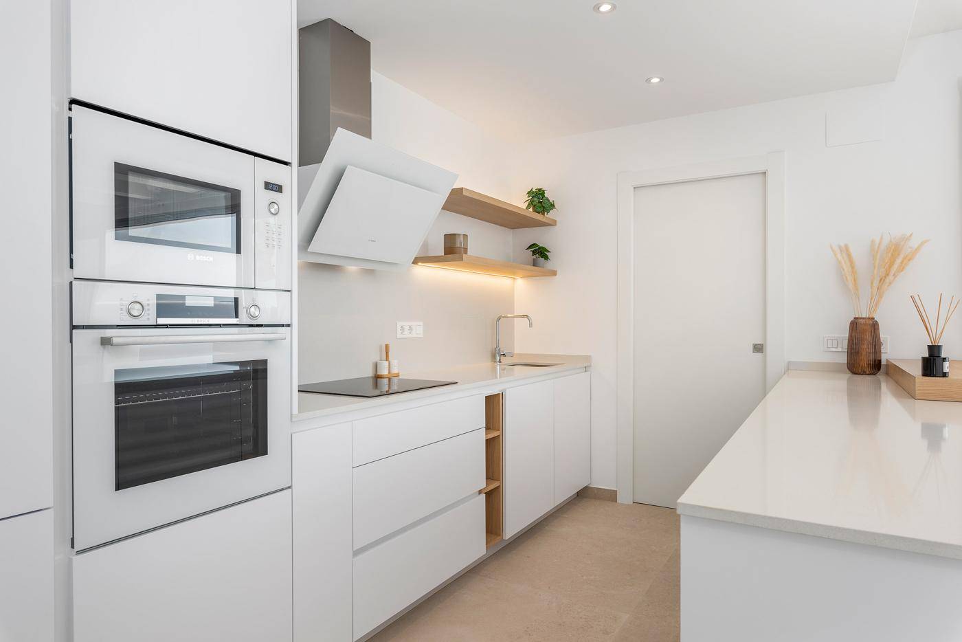 Moderne Einbauküche mit weißen Fronten, Holzregalen und hochwertigen Geräten.