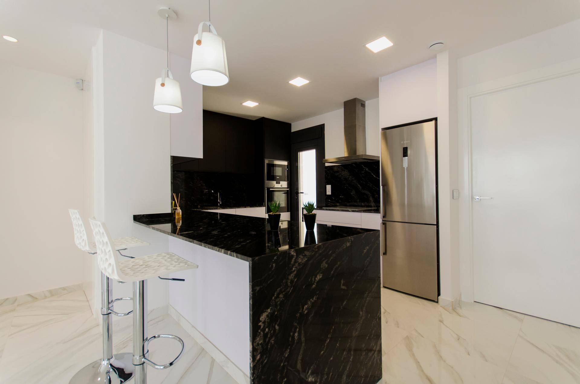 Moderne Küche mit schwarzer Granit-Arbeitsplatte, Kücheninsel und Edelstahlgeräten.