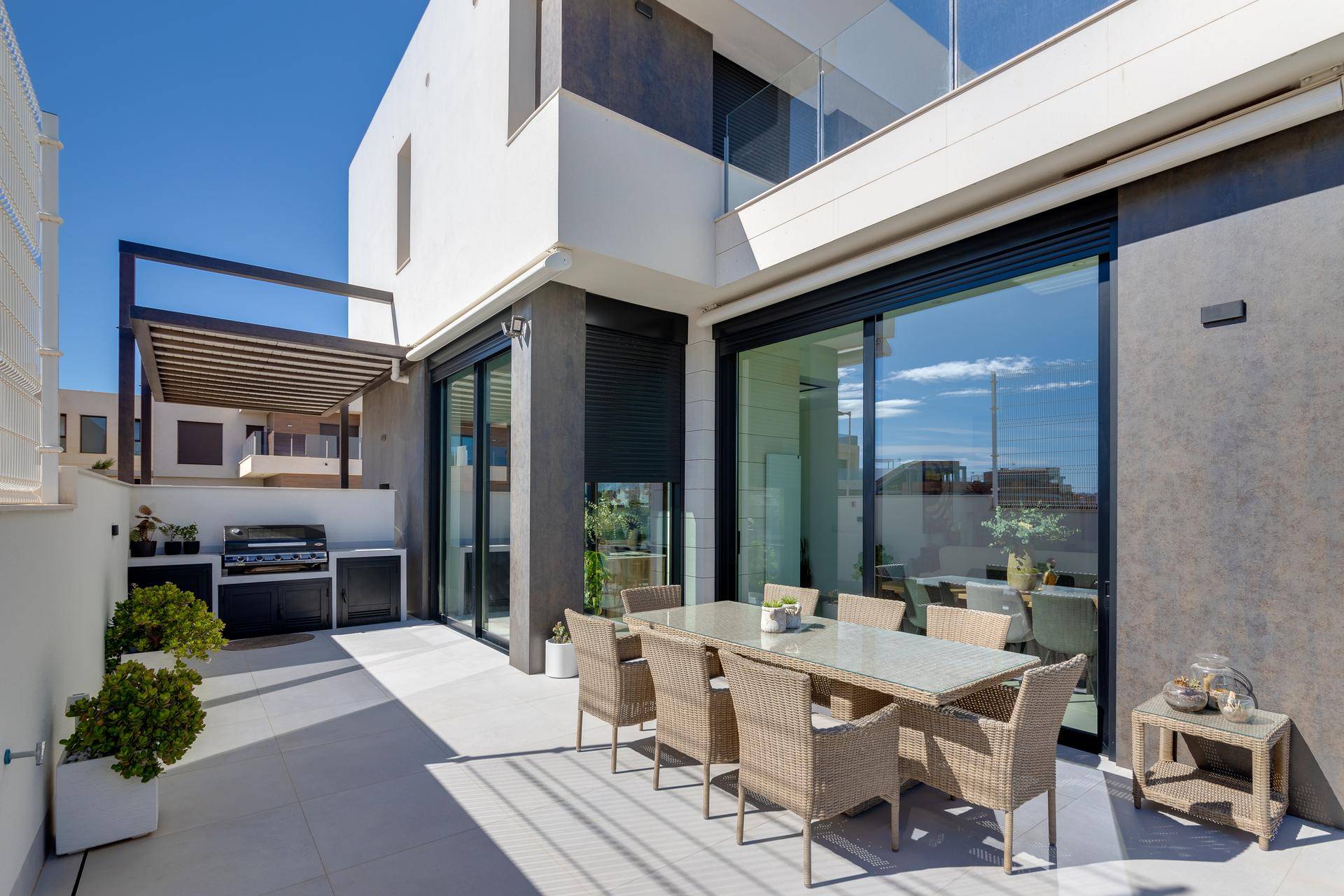Geräumige Terrasse mit Essbereich, Grillstation und direktem Zugang zum modernen Innenbereich des Hauses.