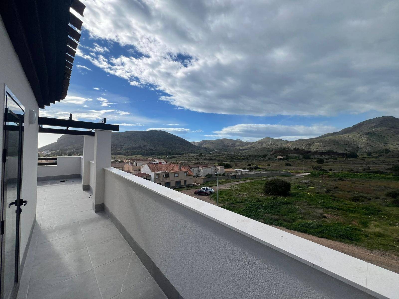 Langer Balkon mit Fliesenboden und weitem Blick auf die grüne Hügellandschaft.