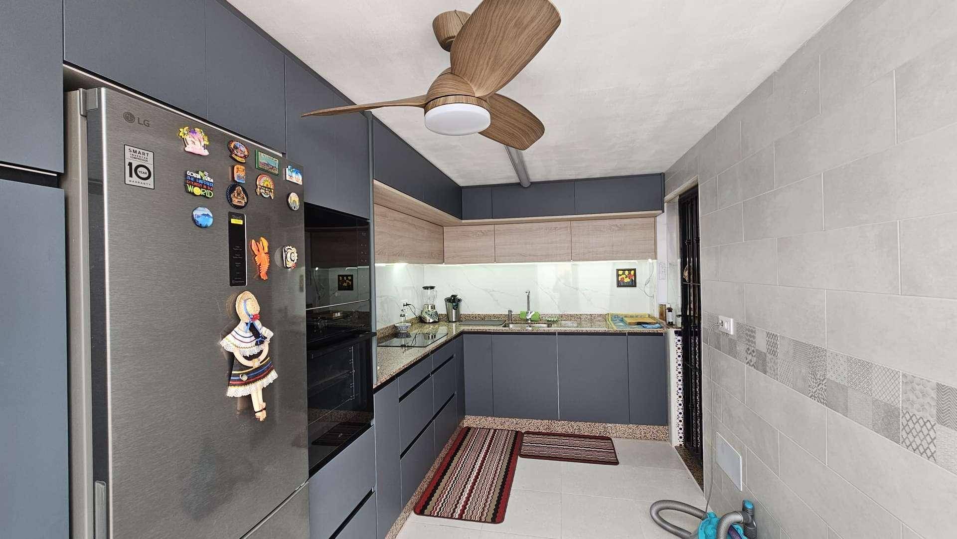 Geräumige Küche mit Deckenventilator, modernen Geräten und hellen Fliesen an den Wänden.