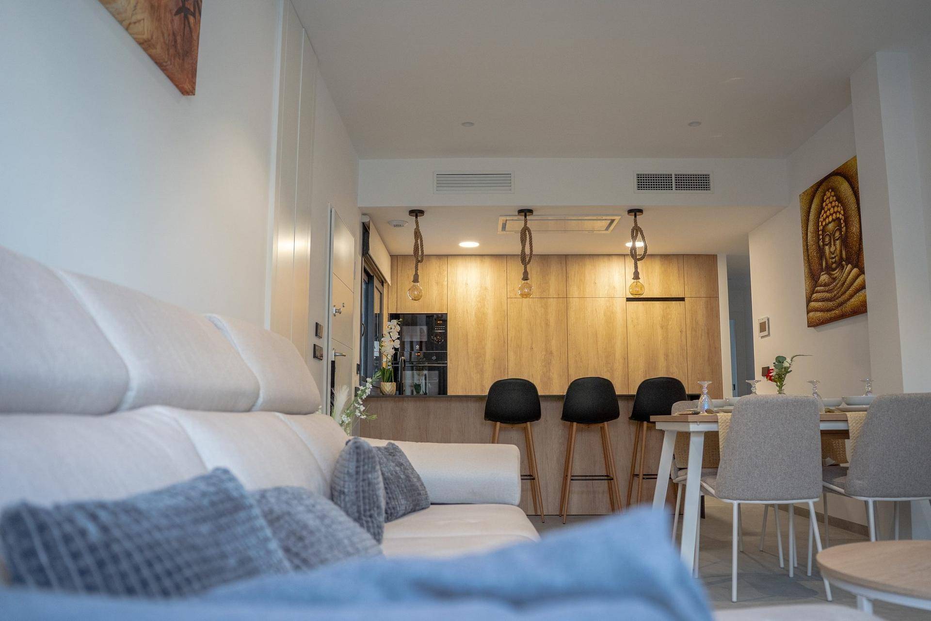 Gemütlicher Wohnbereich mit Sofa und Blick auf die offene Holzküche und den Essbereich.
