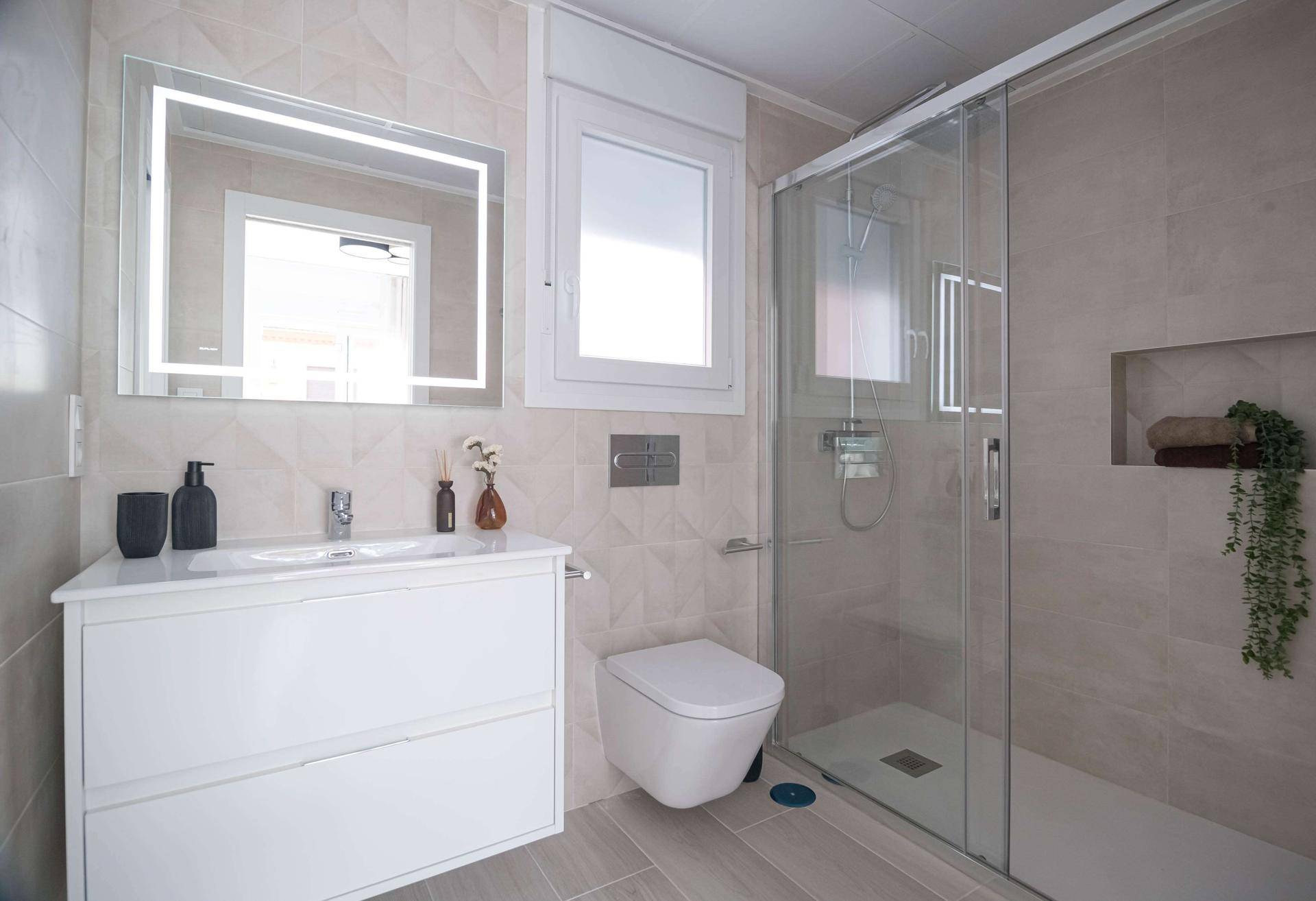 Helles Badezimmer mit moderner Dusche, Waschtisch und beleuchtetem Spiegel.