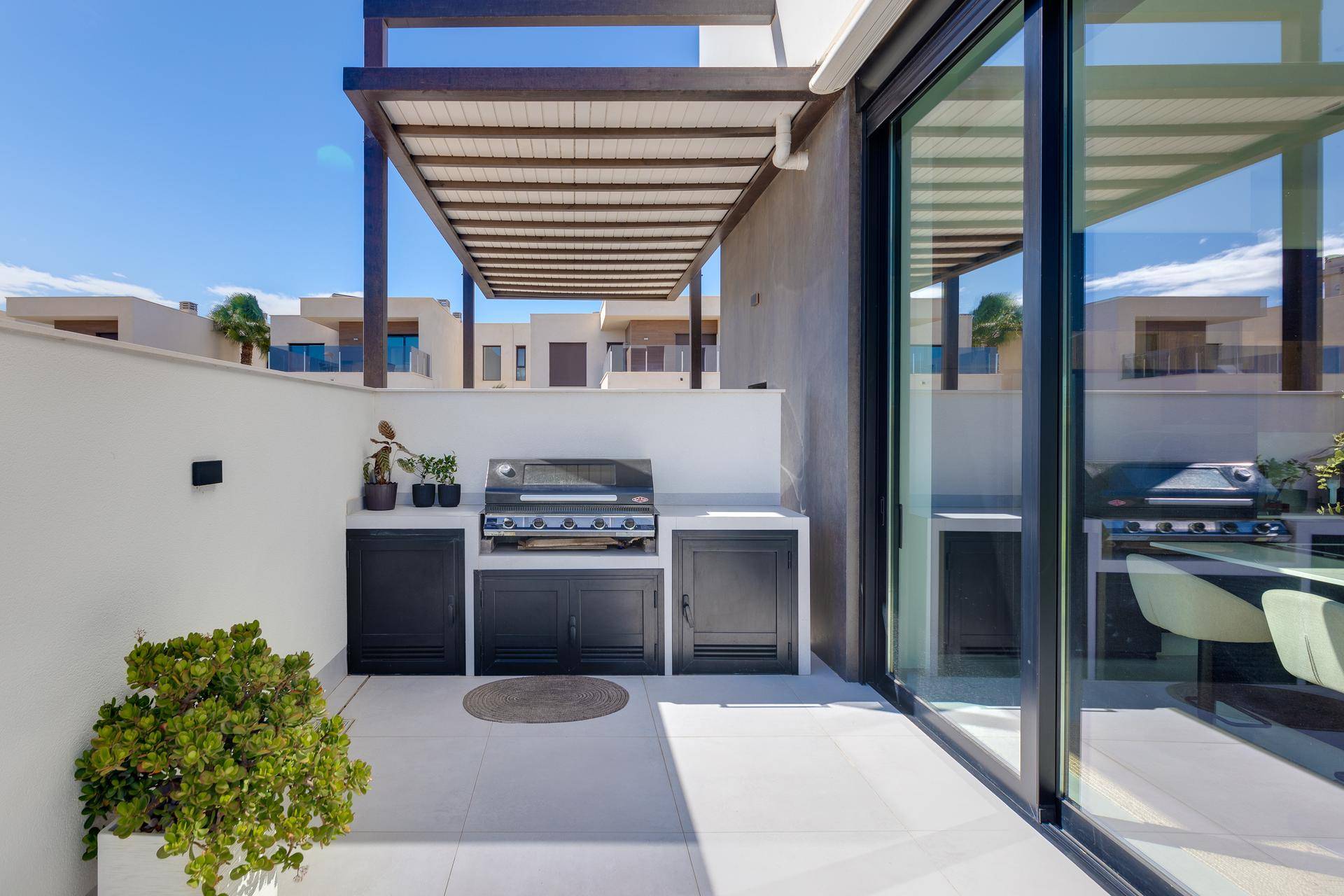 Überdachter Außenbereich mit Grillstation und Essbereich, ideal für Unterhaltung und Entspannung.