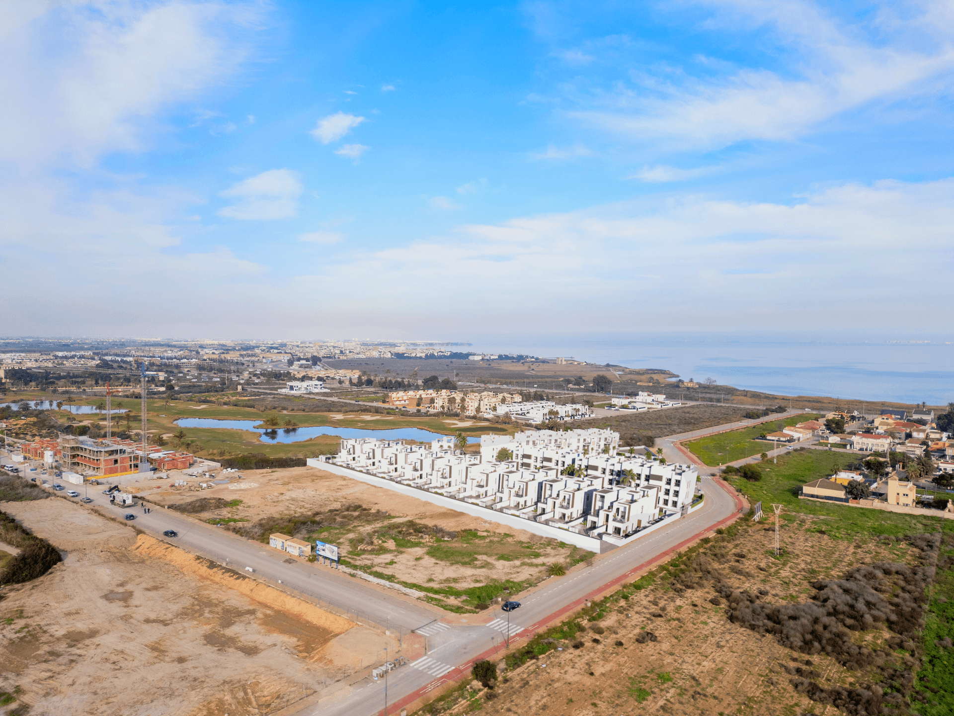 Weitläufige Luftaufnahme einer modernen Wohnanlage mit Blick auf das Meer und die umliegende Landschaft.