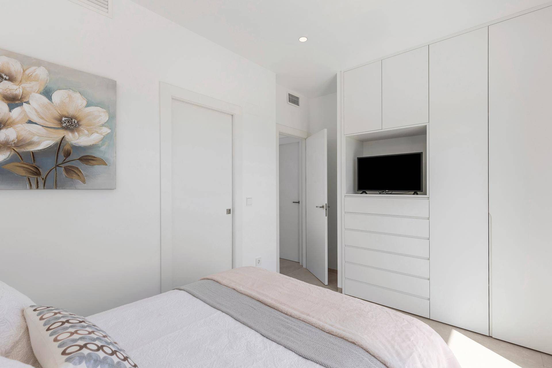 Schlafzimmer mit Einbauschränken, integriertem Fernseher und moderner Einrichtung.