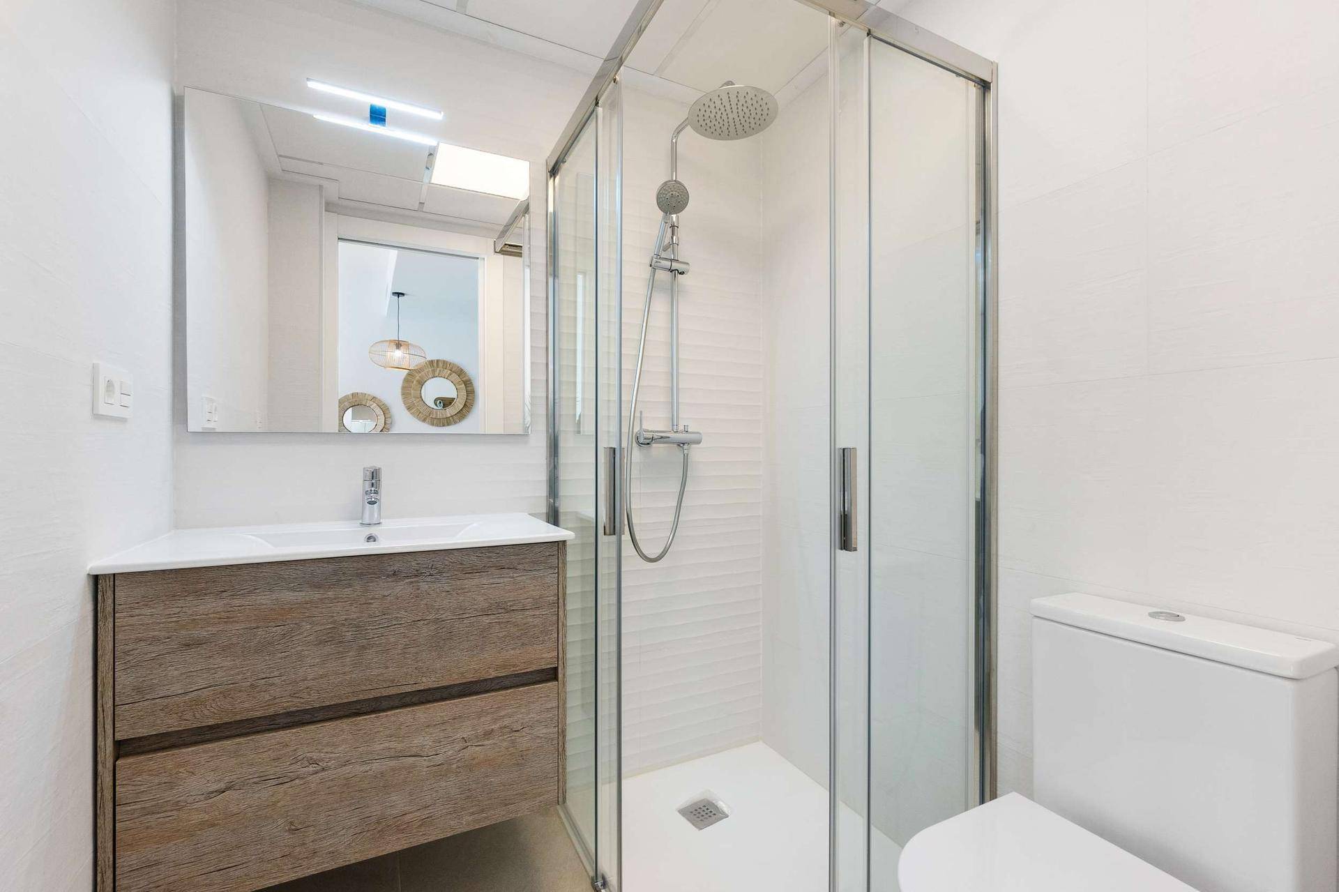Modernes Ensuite-Badezimmer mit Duschkabine, WC, Waschtisch und großem Spiegel.