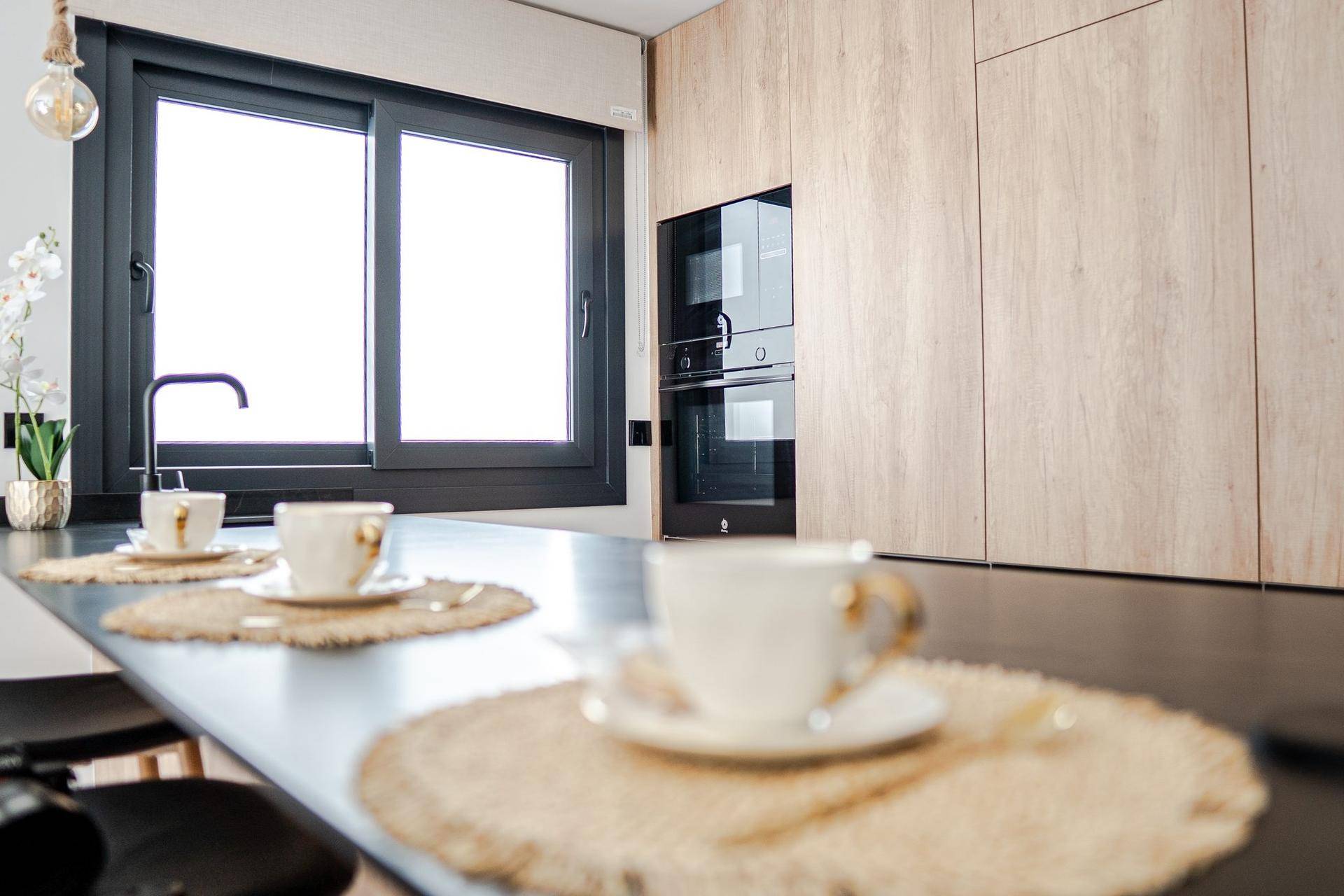Helle Küche mit Fenster, dunkler Arbeitsplatte und integrierten Backöfen.