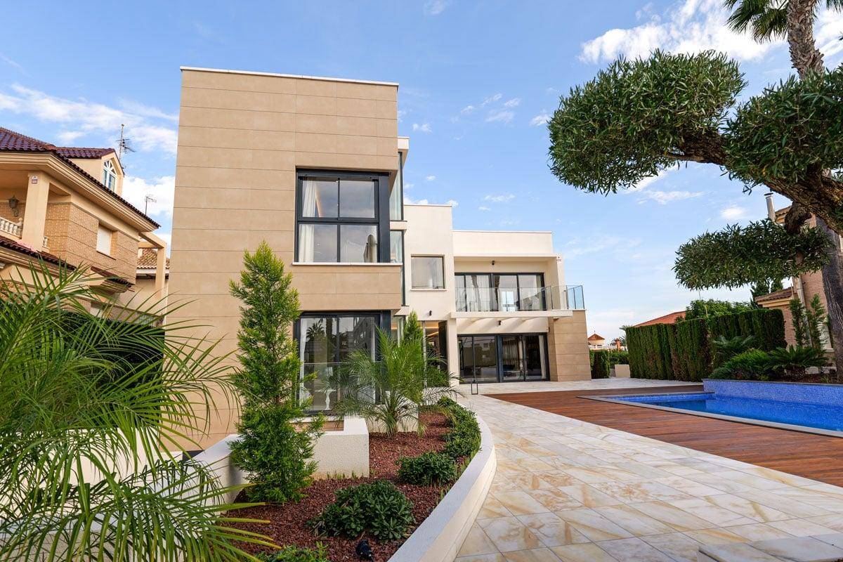 Elegante Villa mit weitläufigem Poolbereich, Holzdeck und mediterraner Bepflanzung.