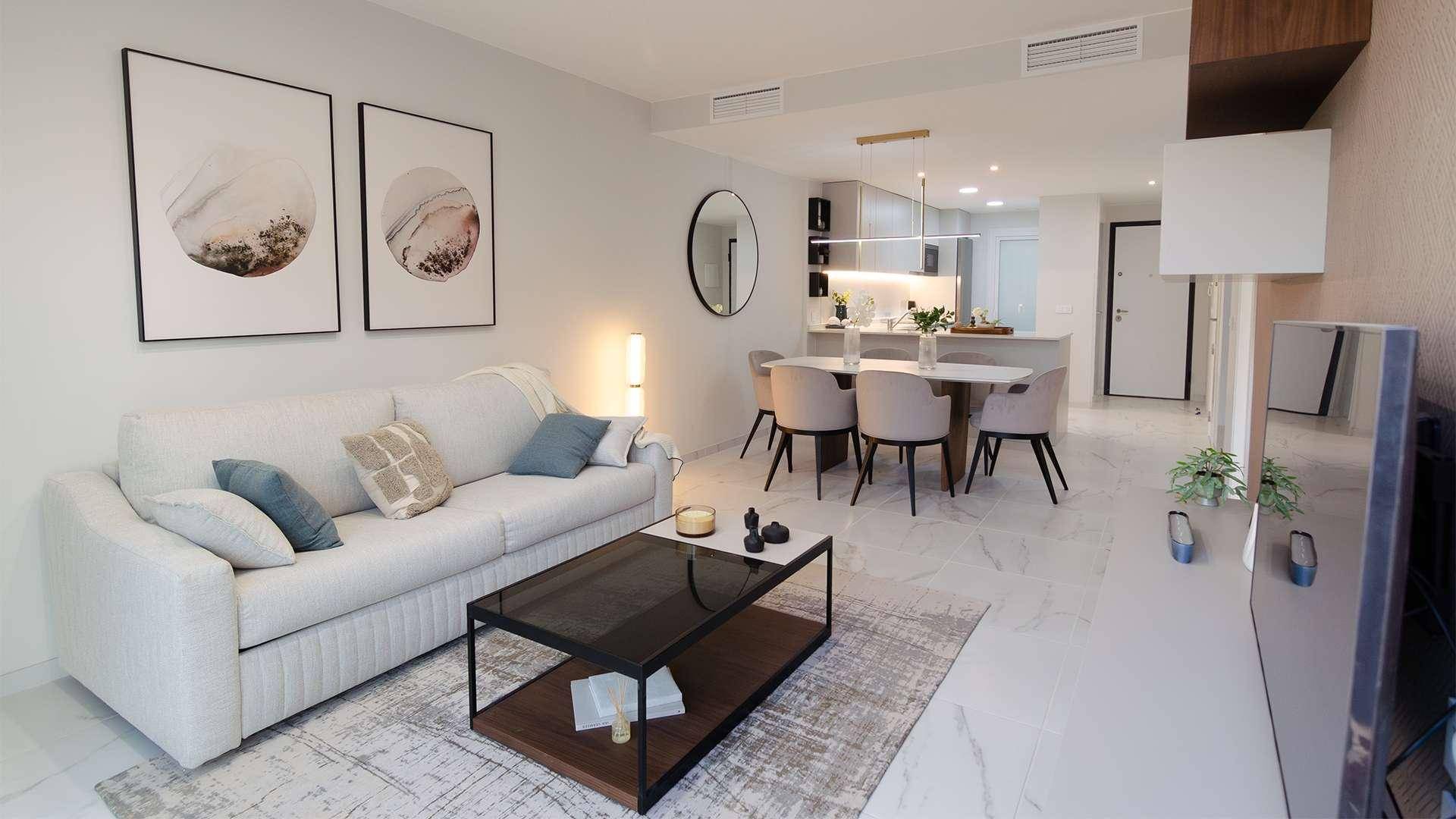 Heller Wohn-Essbereich mit stilvollem Sofa, Esstisch und offener Küche in zeitgemäßem Stil.