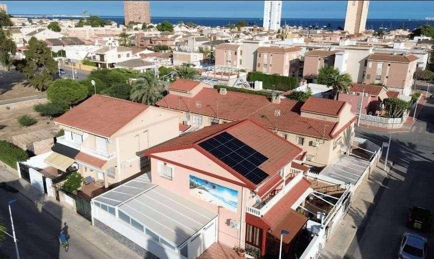 Luftaufnahme des Hauses mit Solarpaneelen auf dem Dach und Blick auf die Küstenstadt.