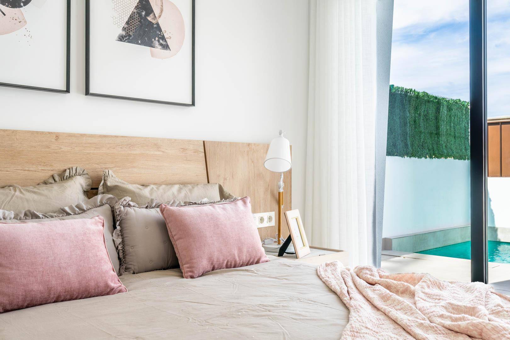 Helles Schlafzimmer mit Holzkopfteil und direktem Zugang zum Poolbereich.