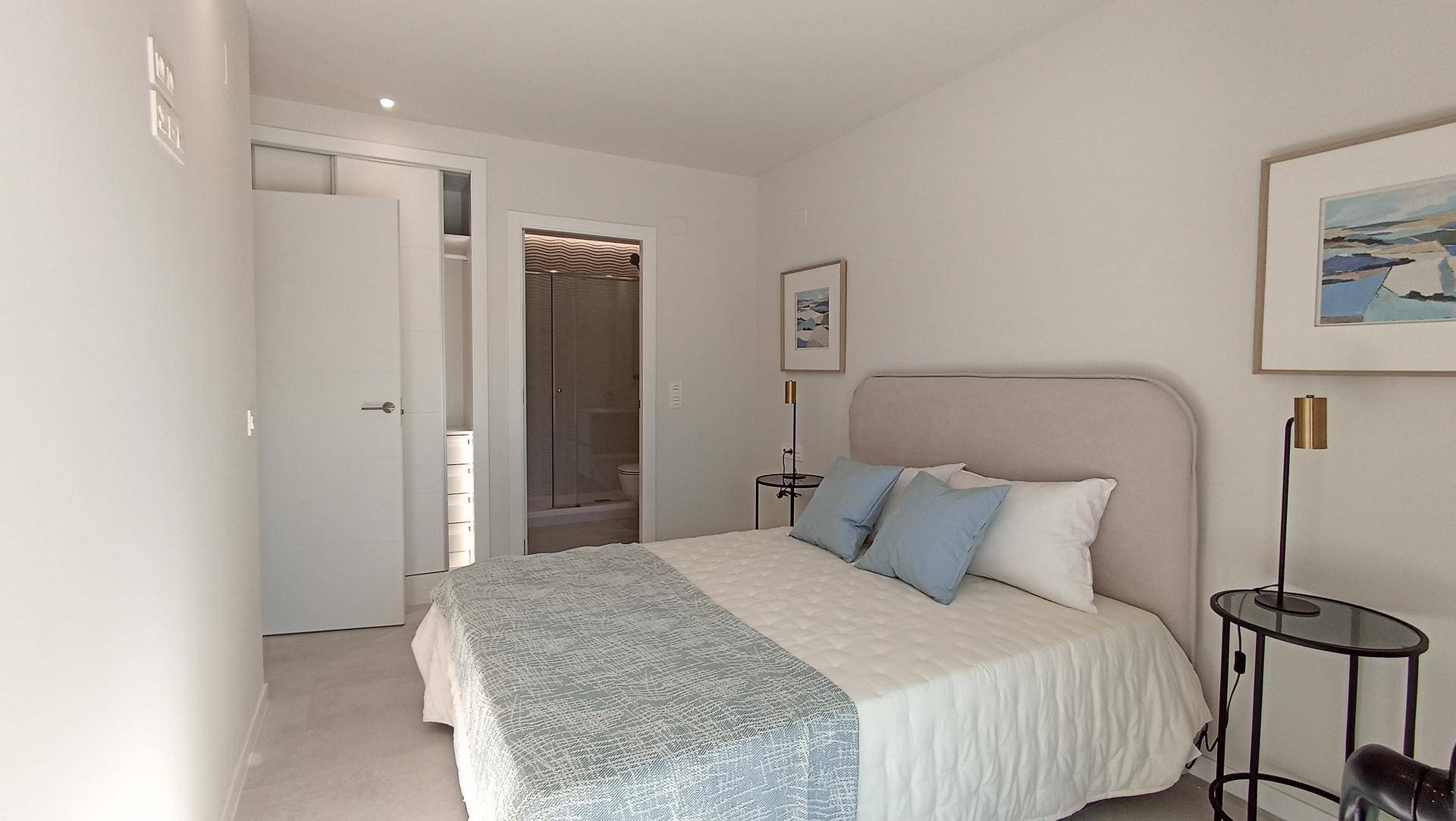 Modernes Schlafzimmer mit Doppelbett, Nachttischen und Zugang zu einem Bad.
