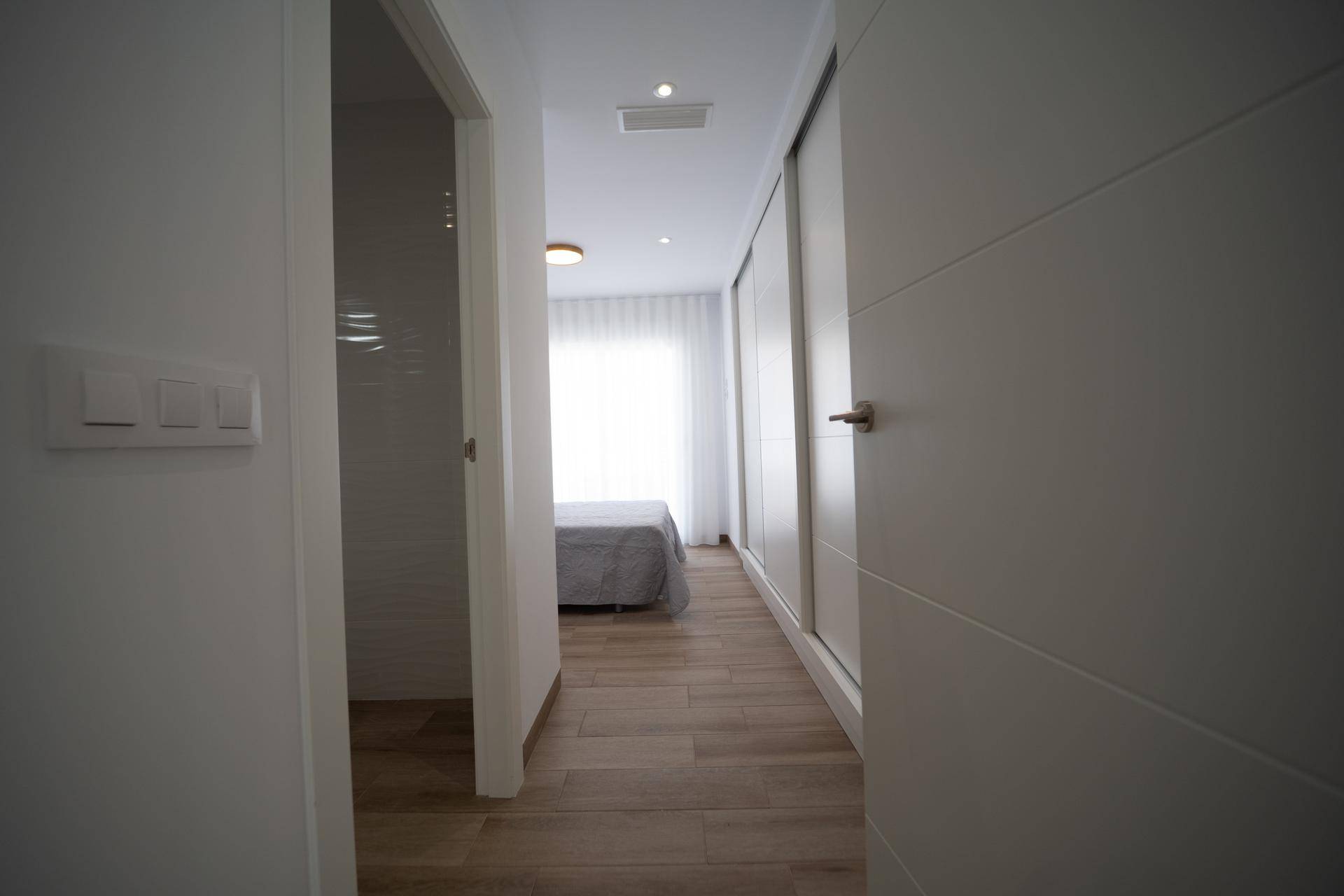Heller Flur mit Zugang zu einem Schlafzimmer mit Einbauschränken.