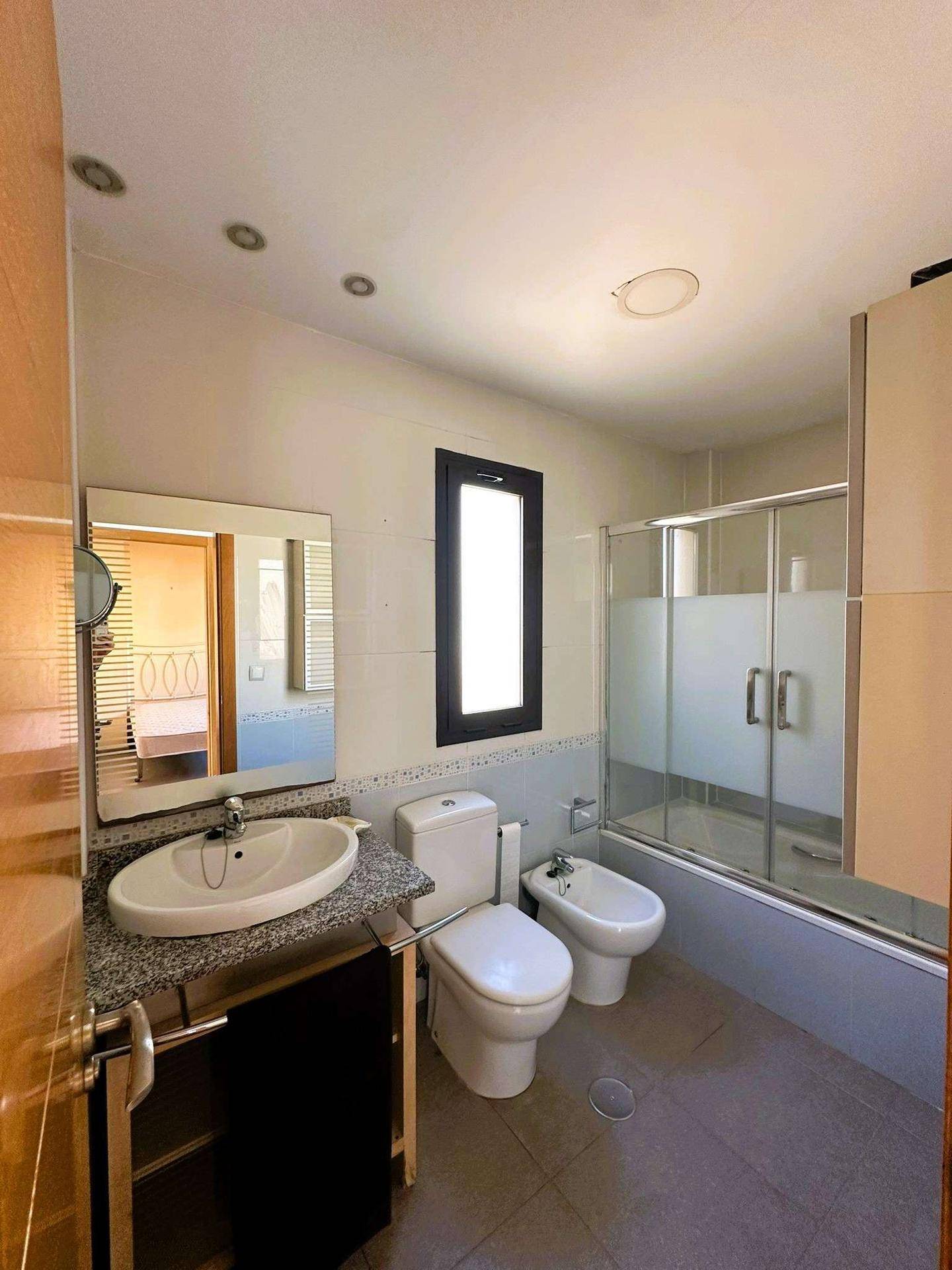 Funktionales Badezimmer mit Dusche, Bidet, Einzelwaschbecken und einem Fenster.