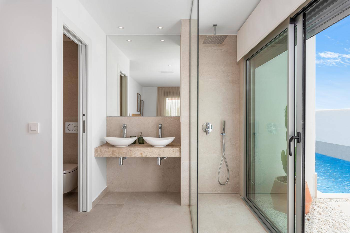 Modernes Badezimmer mit Doppelwaschbecken, begehbarer Dusche und Poolblick.