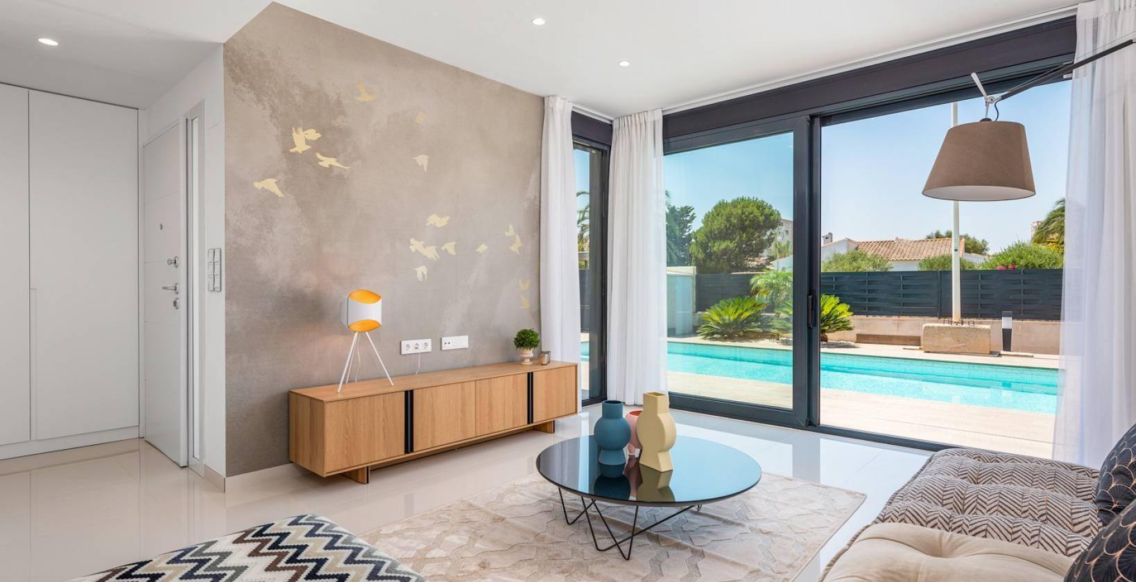 Helles Wohnzimmer mit modernen Möbeln, dekorativer Wand und Blick auf den Pool.