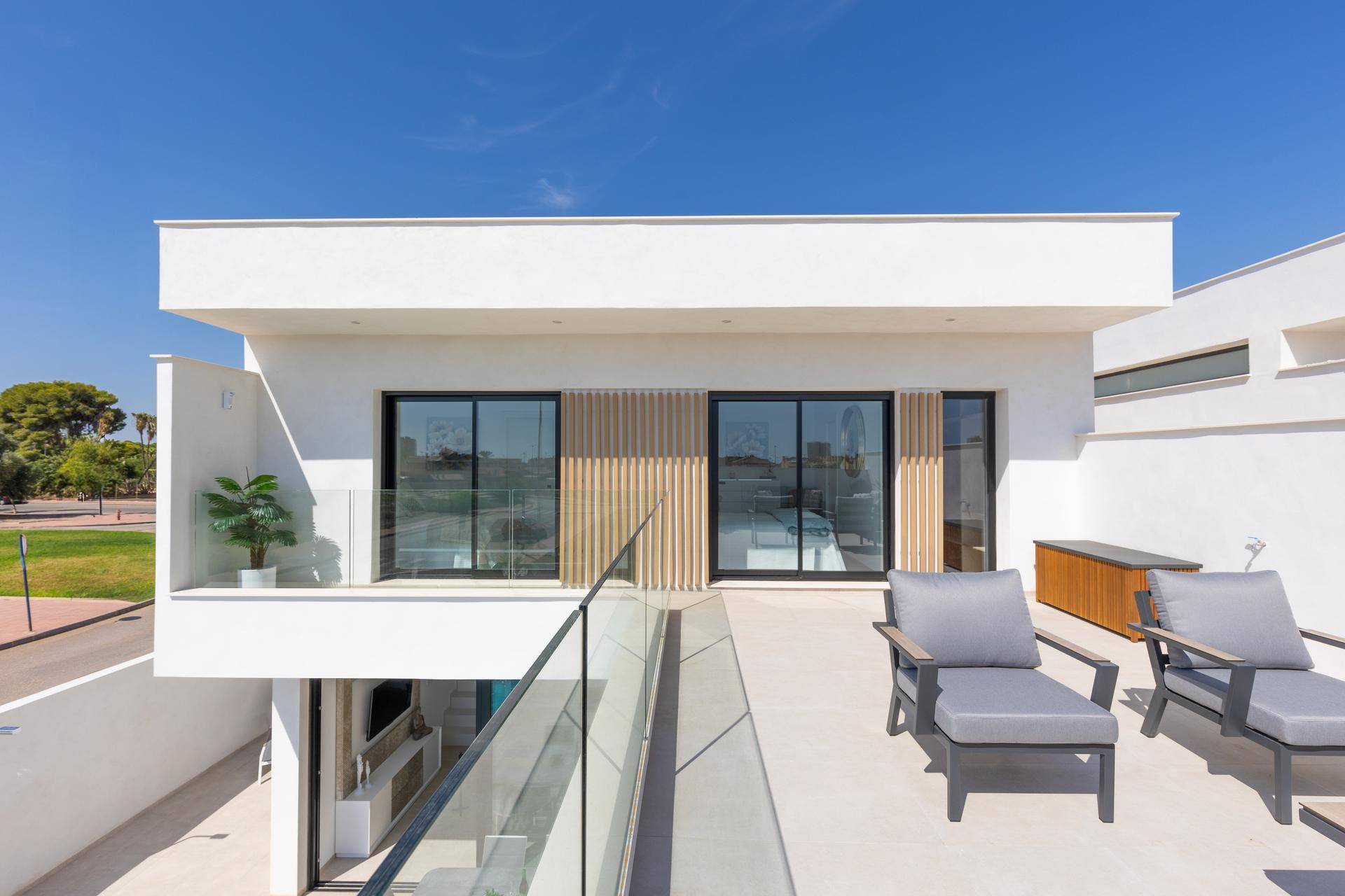 Sonniger Terrassenbereich im Obergeschoss mit Loungemöbeln und moderner Architektur.
