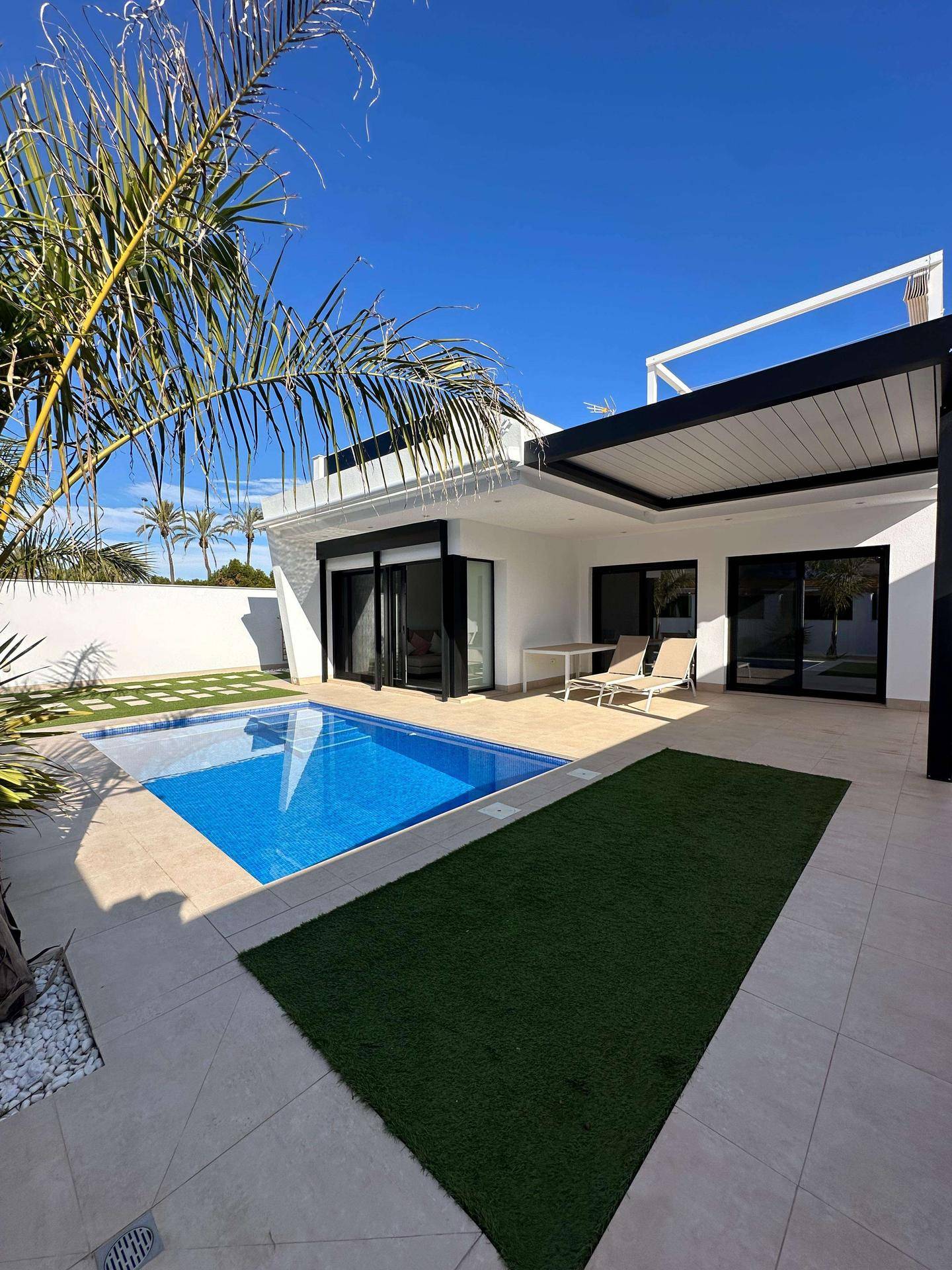 Geräumiger Außenbereich mit Pool, Kunstrasen und überdachter Terrasse für entspannte Stunden.