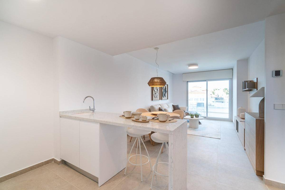 Offener Wohn-Essbereich mit moderner Küche, Frühstücksbar und Zugang zum Balkon.