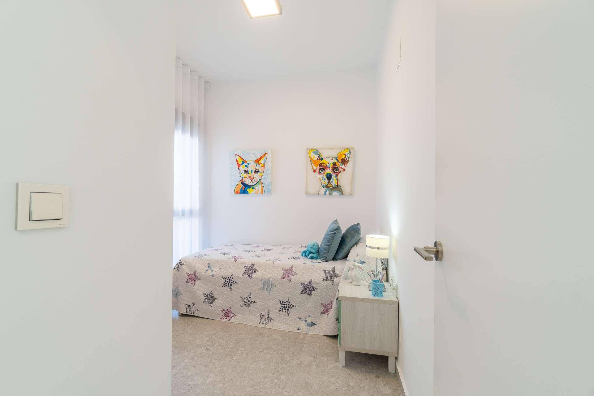 Kinderzimmer mit Einzelbett, bunten Bildern und hellem Fenster.