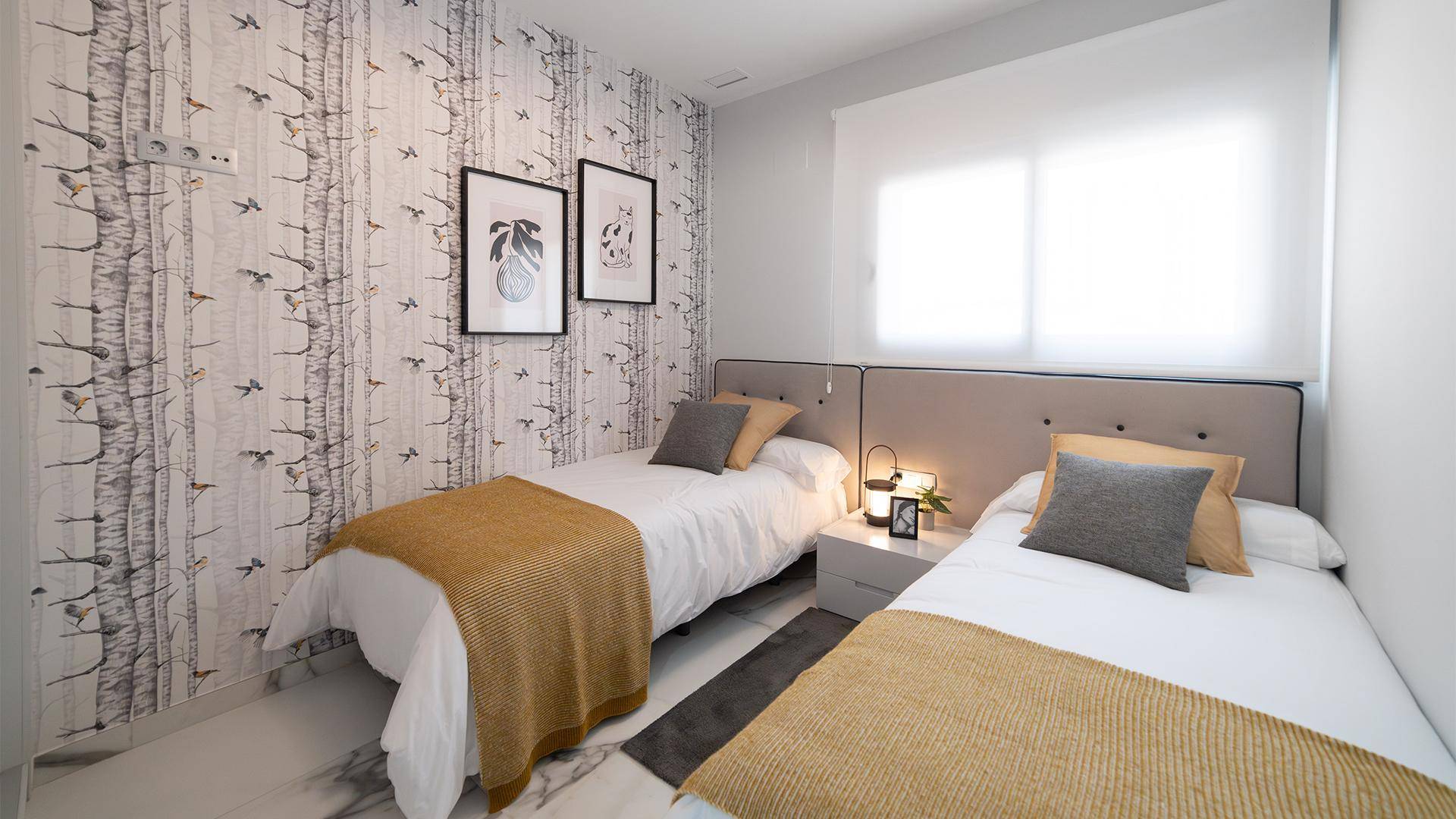 Helles Schlafzimmer mit zwei Einzelbetten, gemusterter Tapete und Tageslicht.