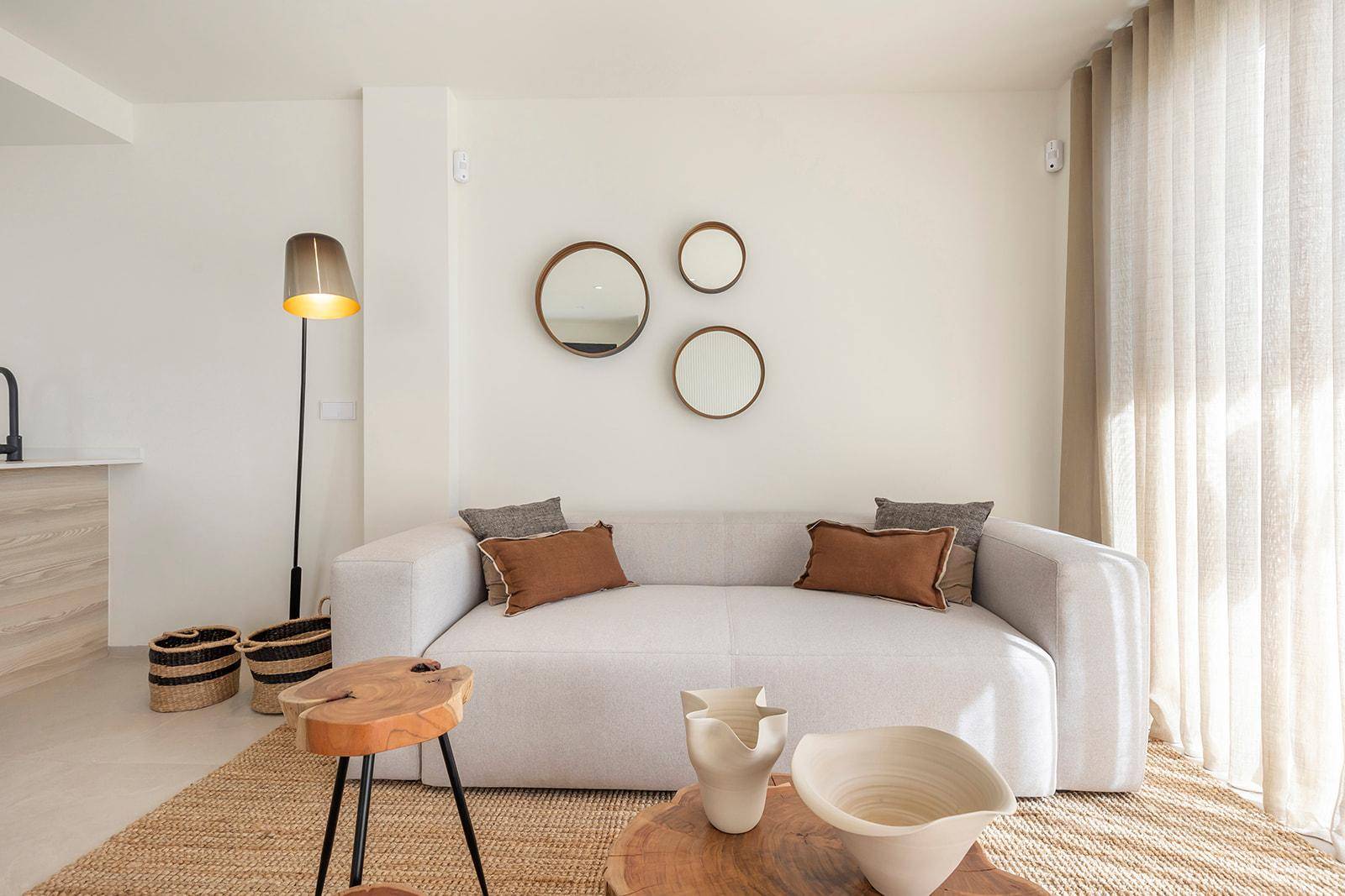 Gemütliches Wohnzimmer mit bequemer Couch, Stehlampe und dekorativen Spiegeln an der Wand.