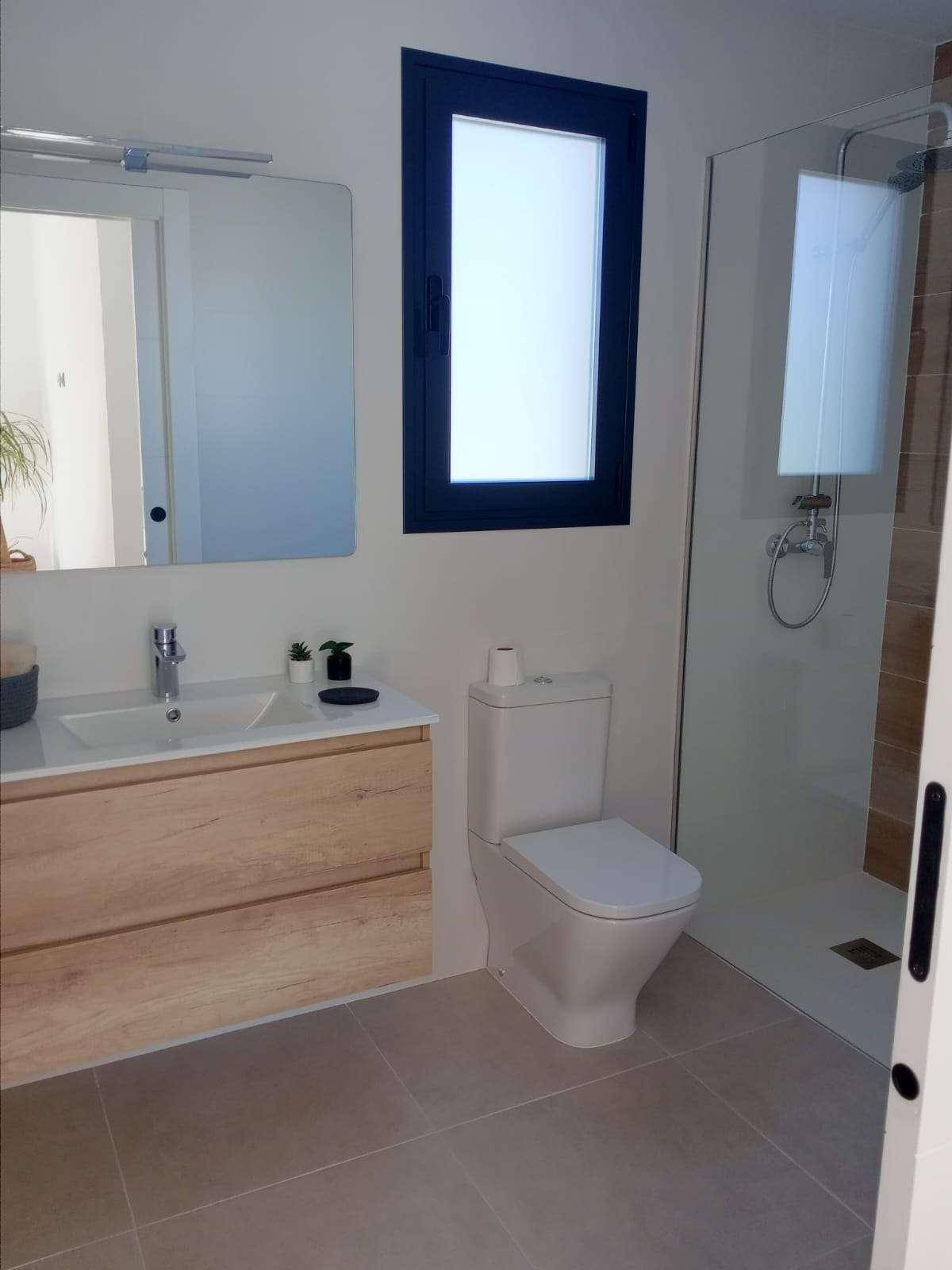 Modernes Badezimmer mit ebenerdiger Dusche, WC und Waschtisch mit Holzunterschrank.