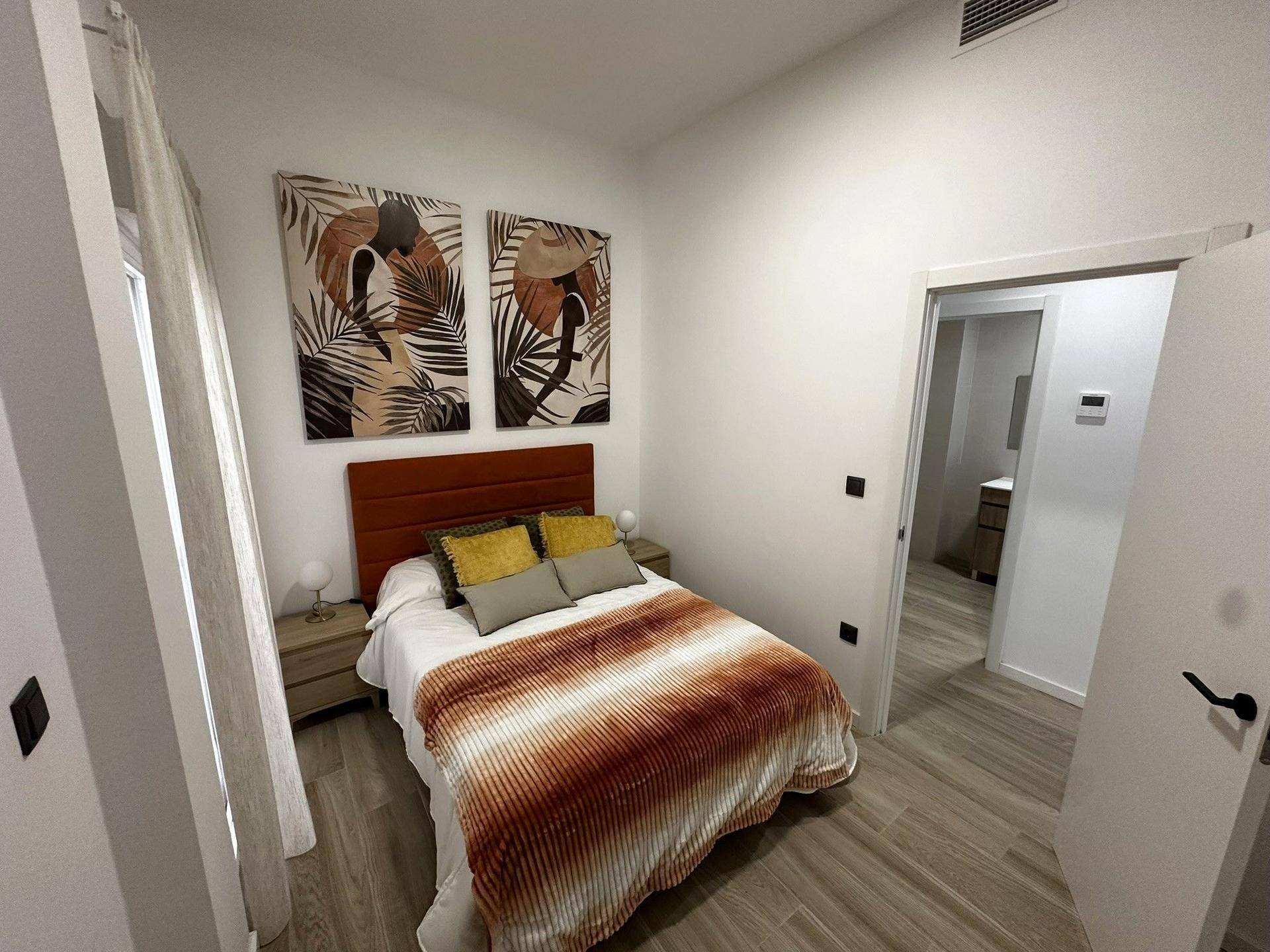 Gemütliches Schlafzimmer mit Doppelbett, farbigen Akzenten und direktem Zugang zu einem Badezimmer.