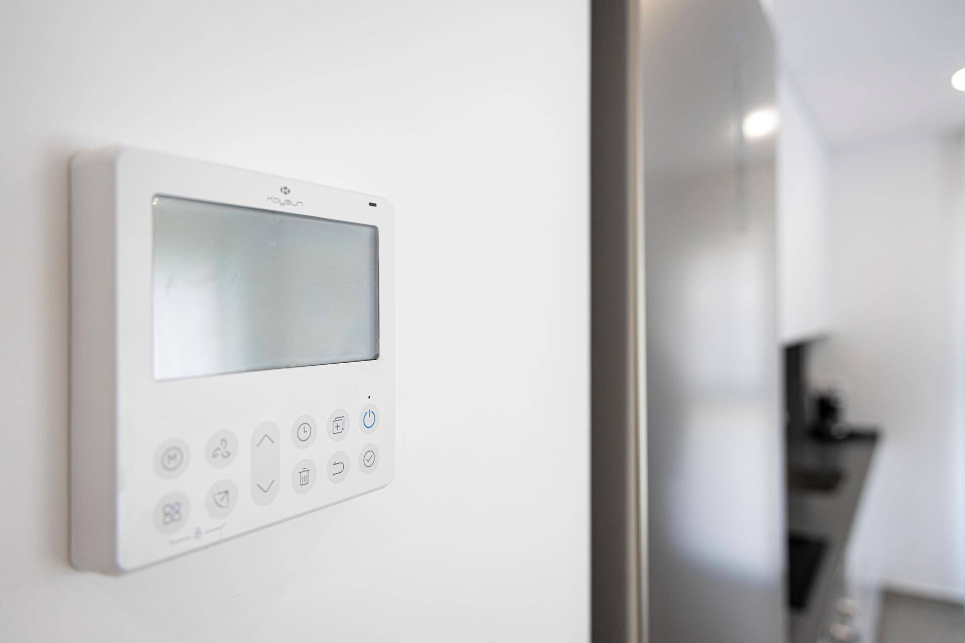 Nahaufnahme eines modernen Smart-Home-Bedienfelds an einer weißen Wand.