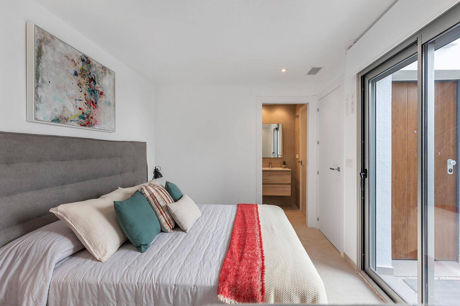 Schlafzimmer mit großem Bett, moderner Kunst und Zugang zu einem privaten Außenbereich.