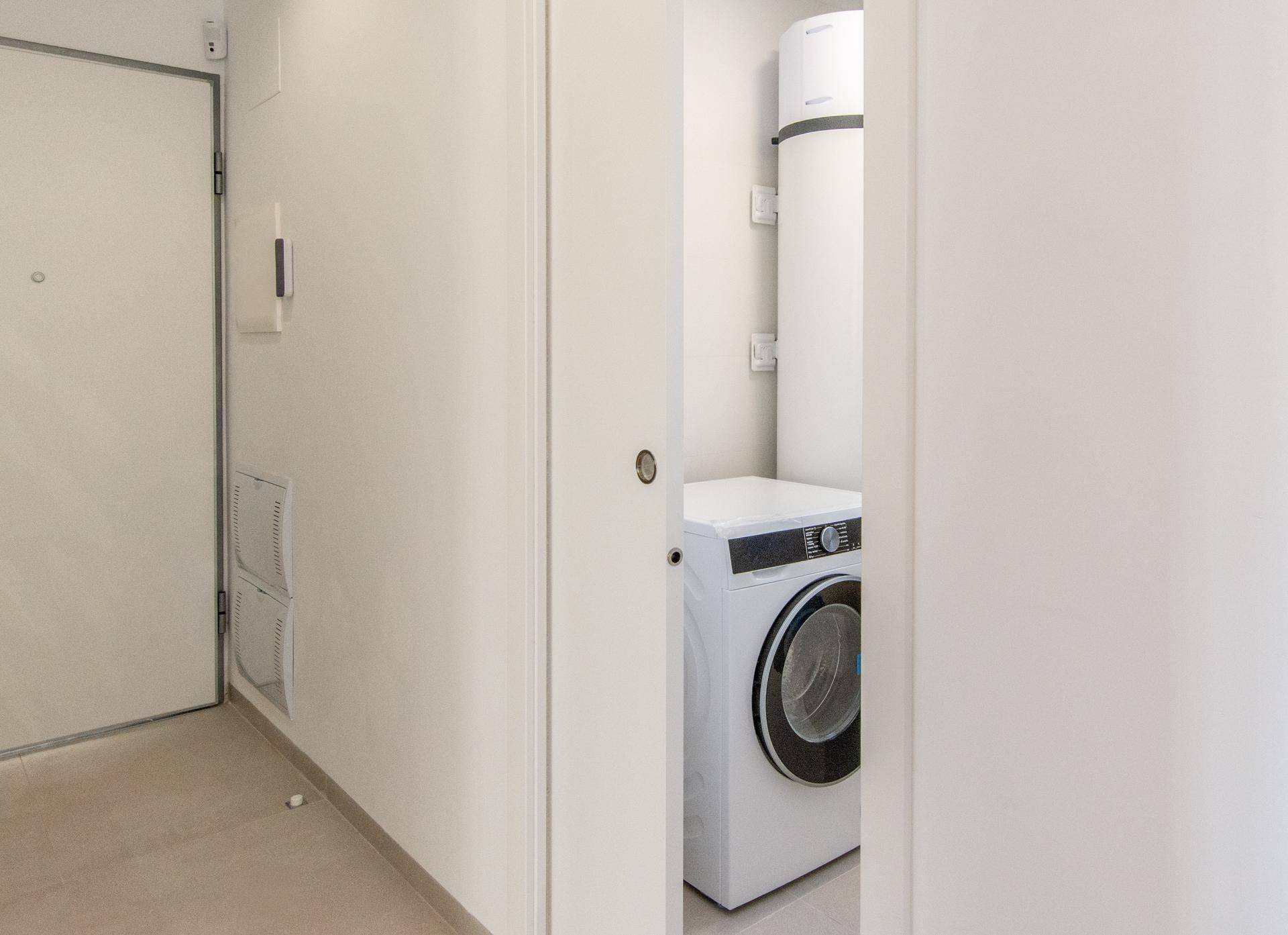 Praktischer Hauswirtschaftsraum mit Waschmaschine und Warmwasserspeicher im Flurbereich.