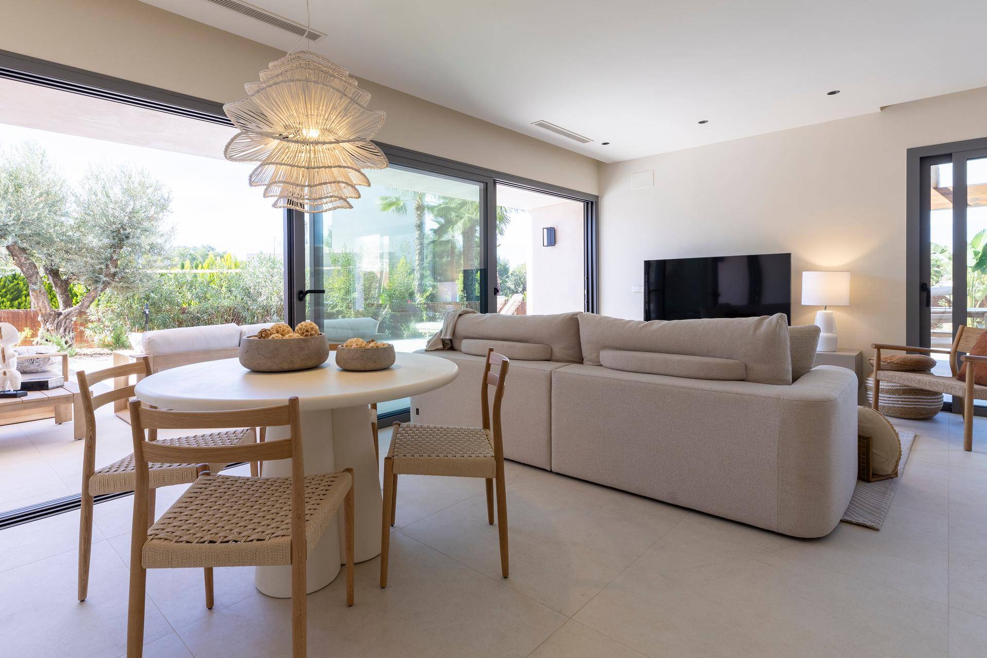 Heller Wohn- und Essbereich mit bequemer Couch und großzügigen Schiebefenstern zur Terrasse.