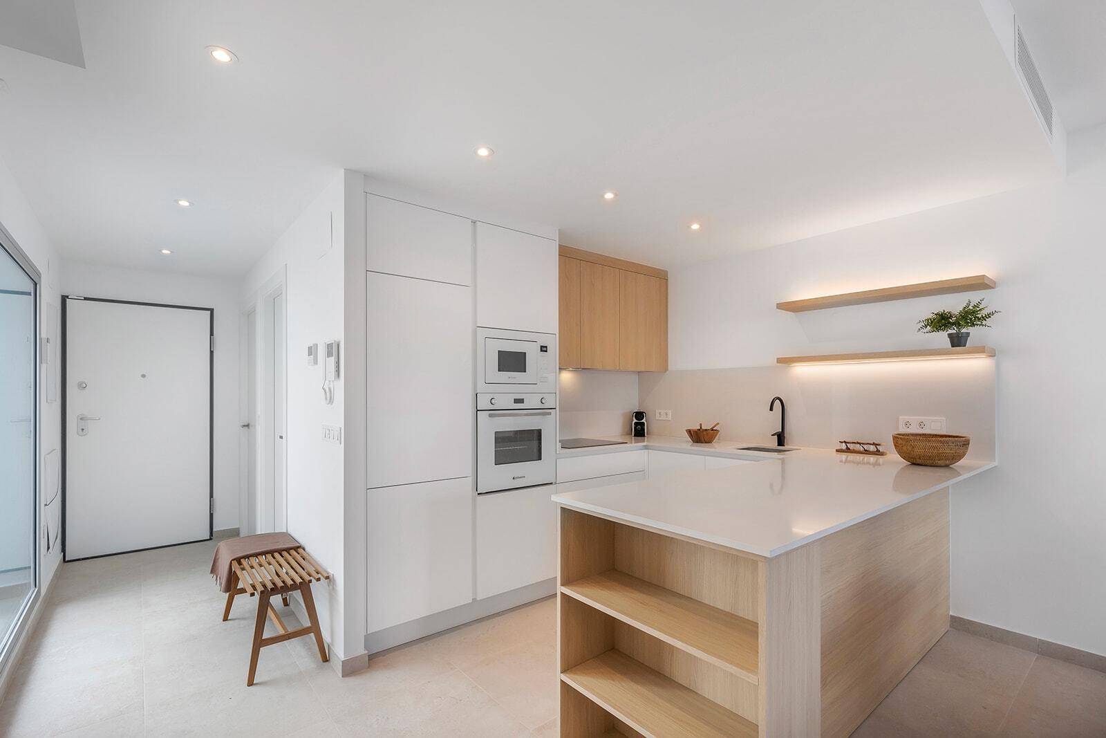 Moderne Küche mit Kochinsel und integrierten Geräten, offen zum Eingangsbereich der Wohnung.