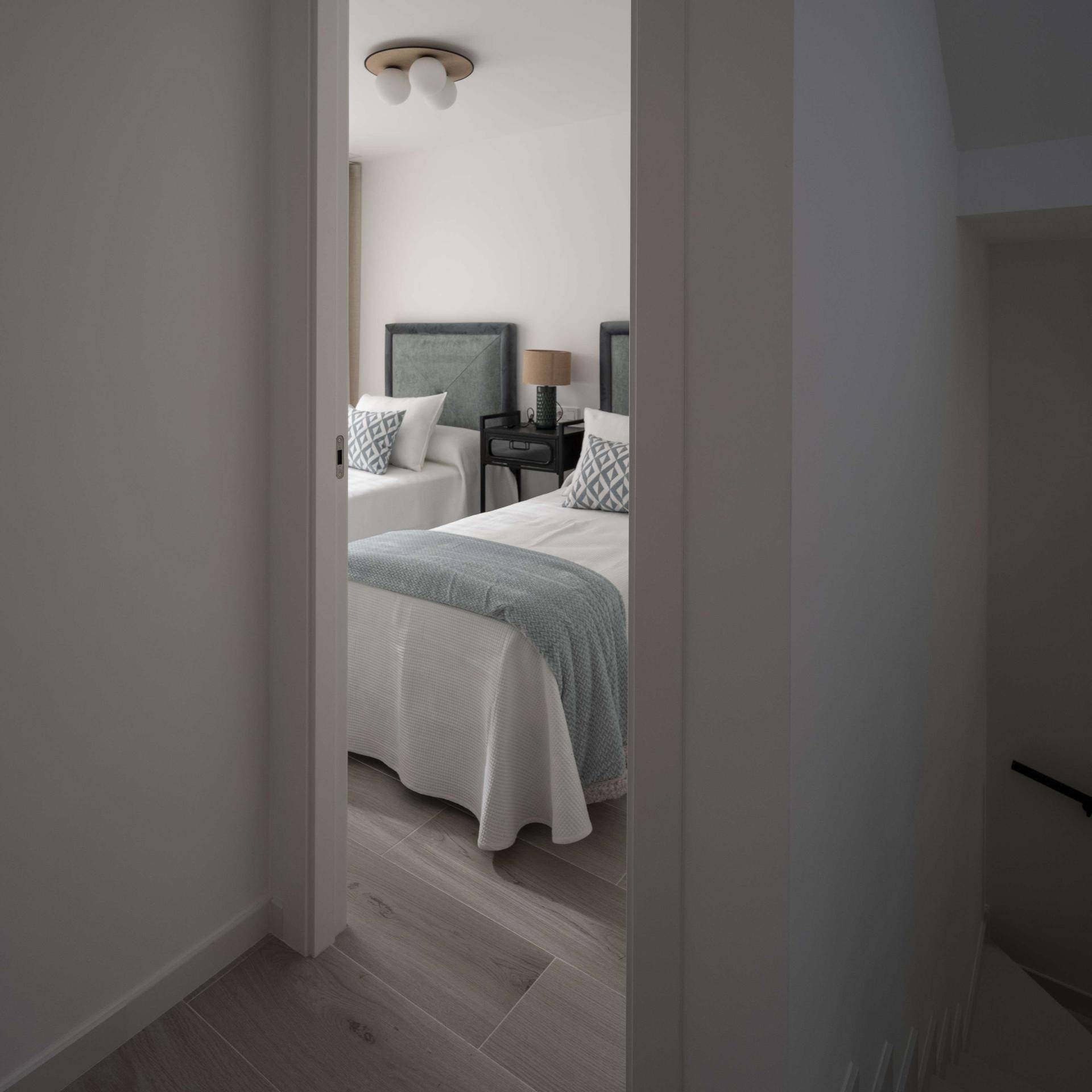 Blick in ein helles Schlafzimmer mit zwei Einzelbetten und moderner Einrichtung.