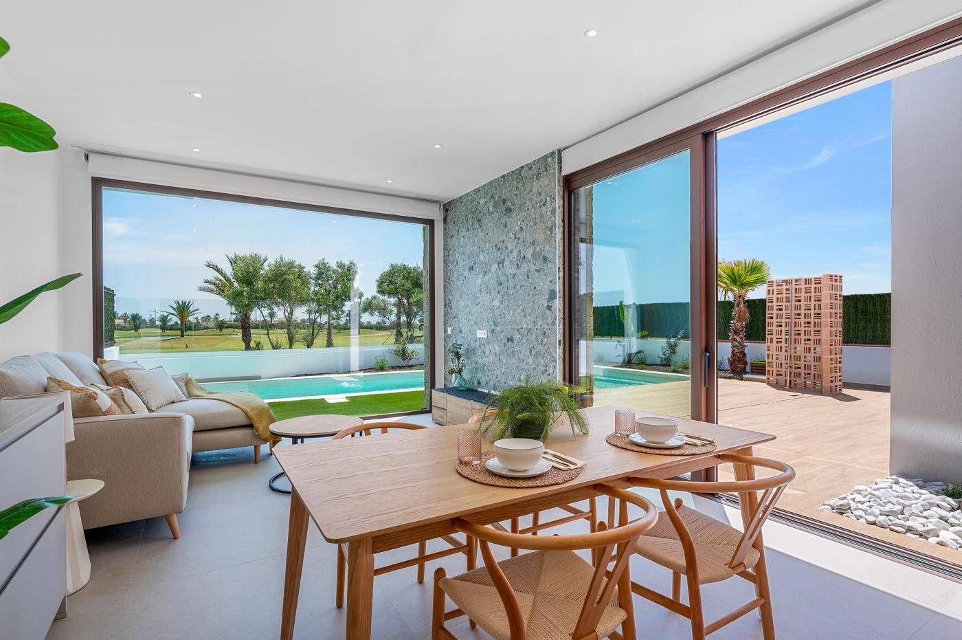 Heller Wohn- und Essbereich mit großen Fenstern, die den Blick auf den Pool und die Landschaft freigeben.