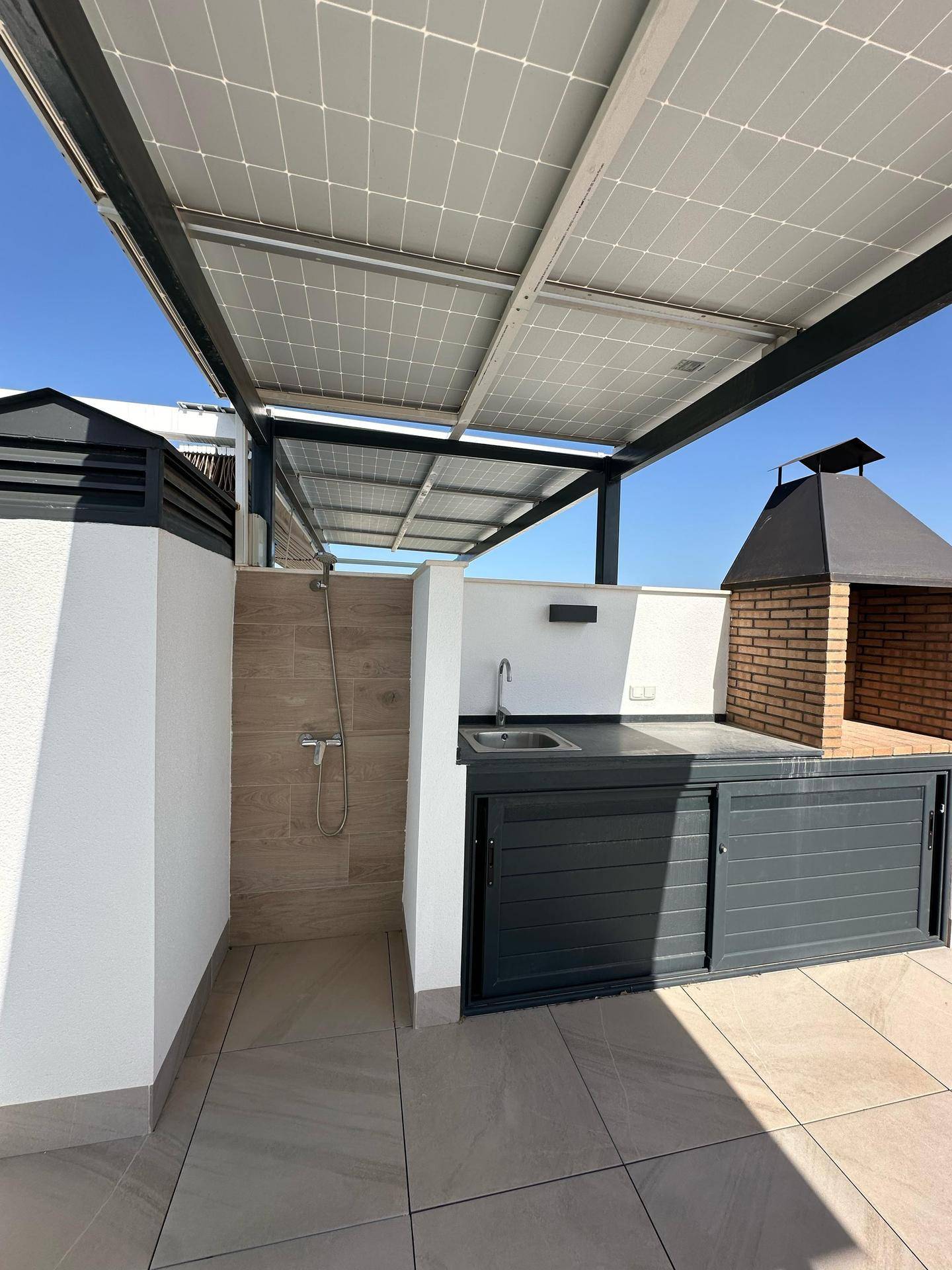 Dachterrasse mit Außenküche, Grillbereich, Dusche und Photovoltaikanlage für nachhaltige Energie.