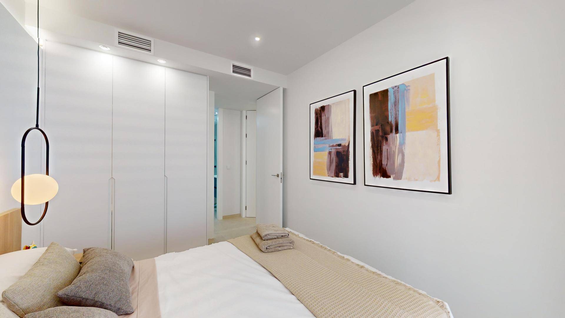 Helles Schlafzimmer mit modernen Einbauschränken, abstrakter Kunst und minimalistischer Beleuchtung.