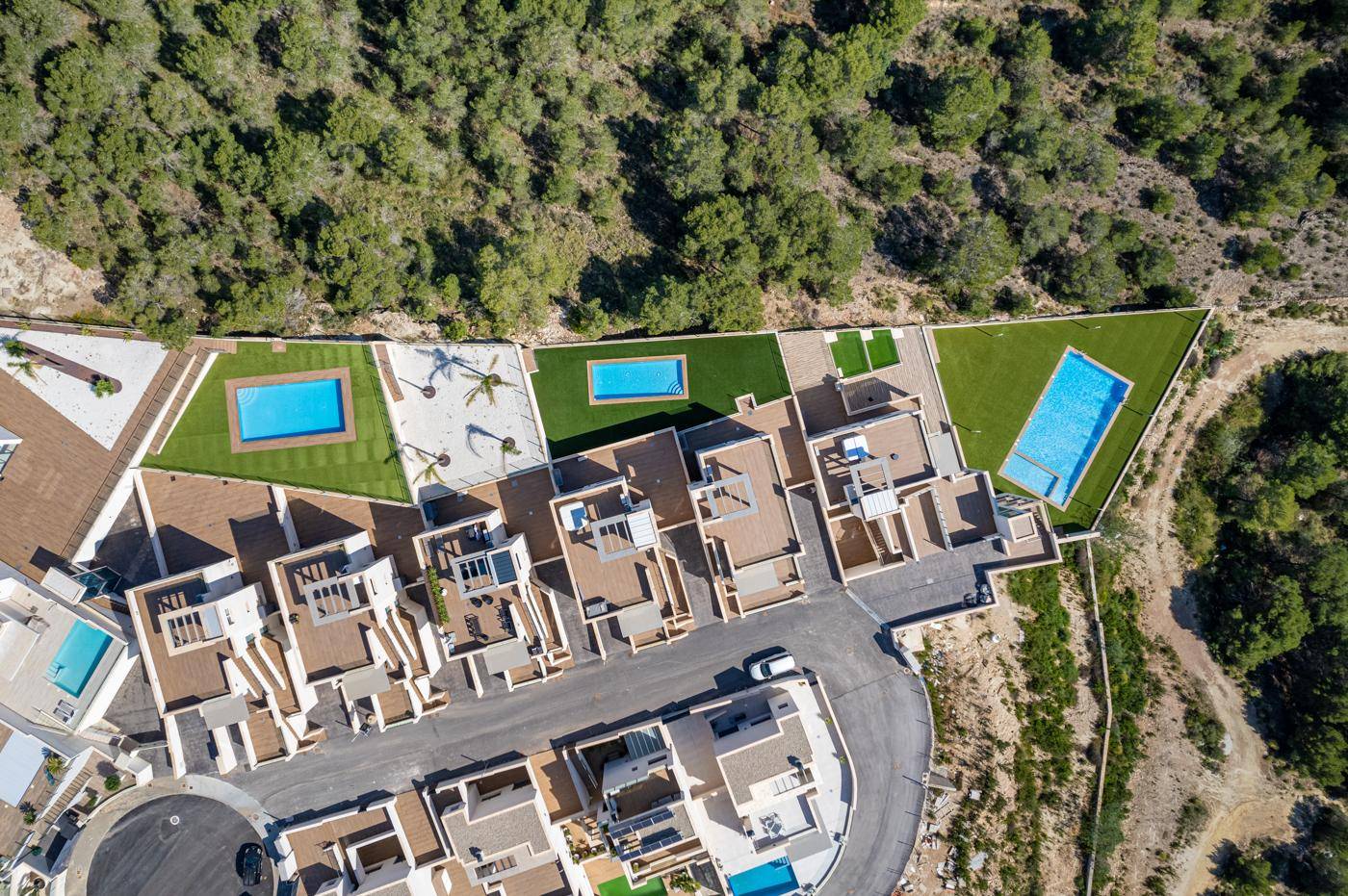 Vogelperspektive auf eine Wohnanlage mit mehreren Pools und begrünten Außenbereichen.