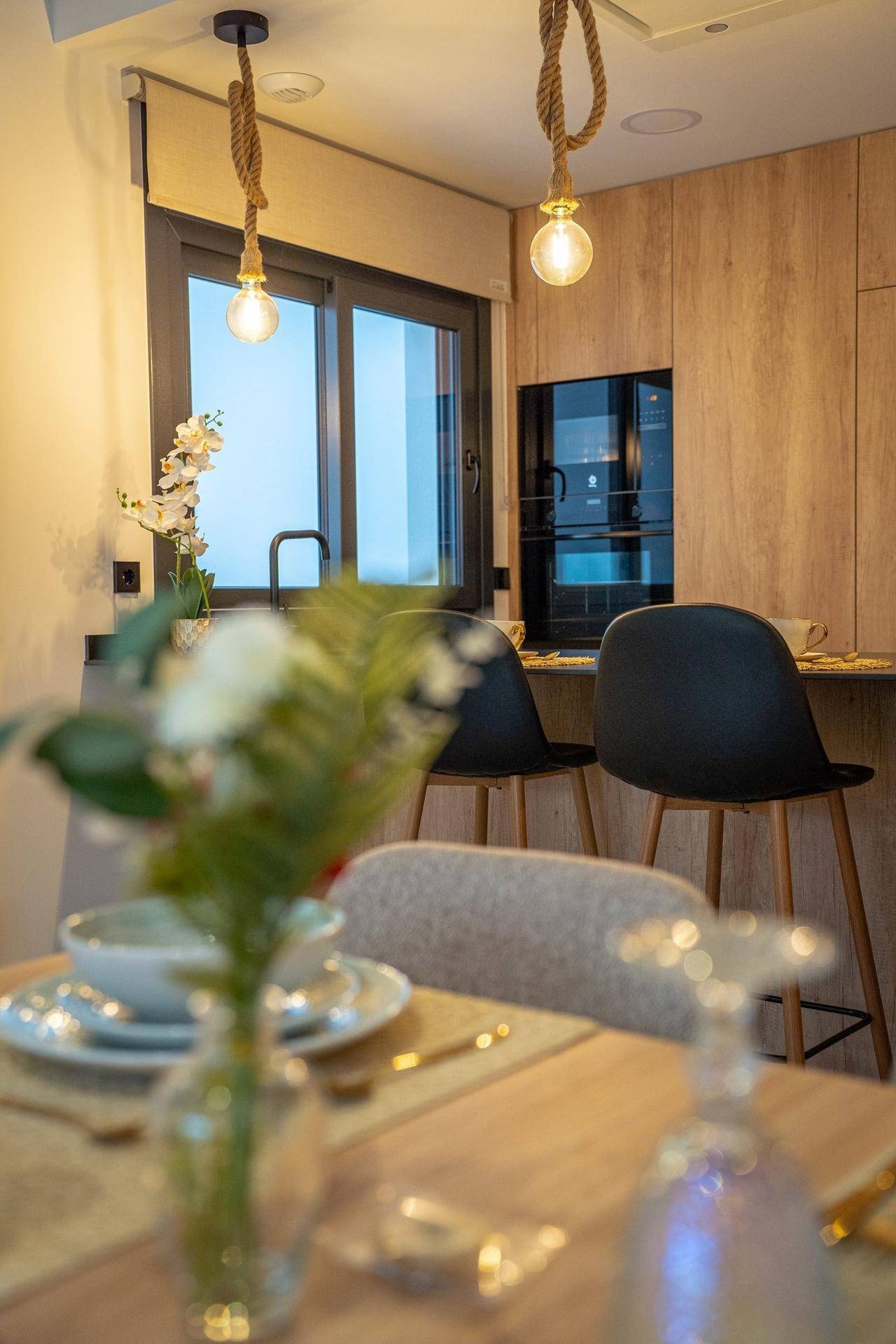Moderne Küche mit Holzfronten, integrierten Geräten und einer Frühstücksbar mit Hockern.