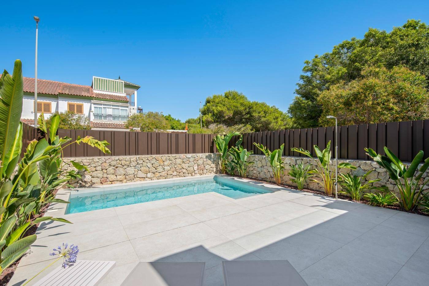 Entspannender Poolbereich mit gefliester Terrasse und tropischen Pflanzen, ideal für sonnige Tage.